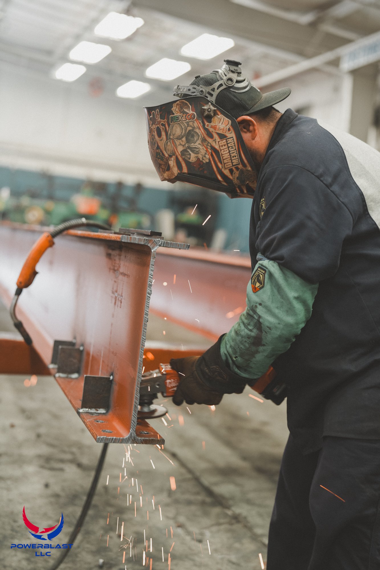 A worker in safety gear welds a metal structure inside an industrial facility, with sparks flying from the welding process.