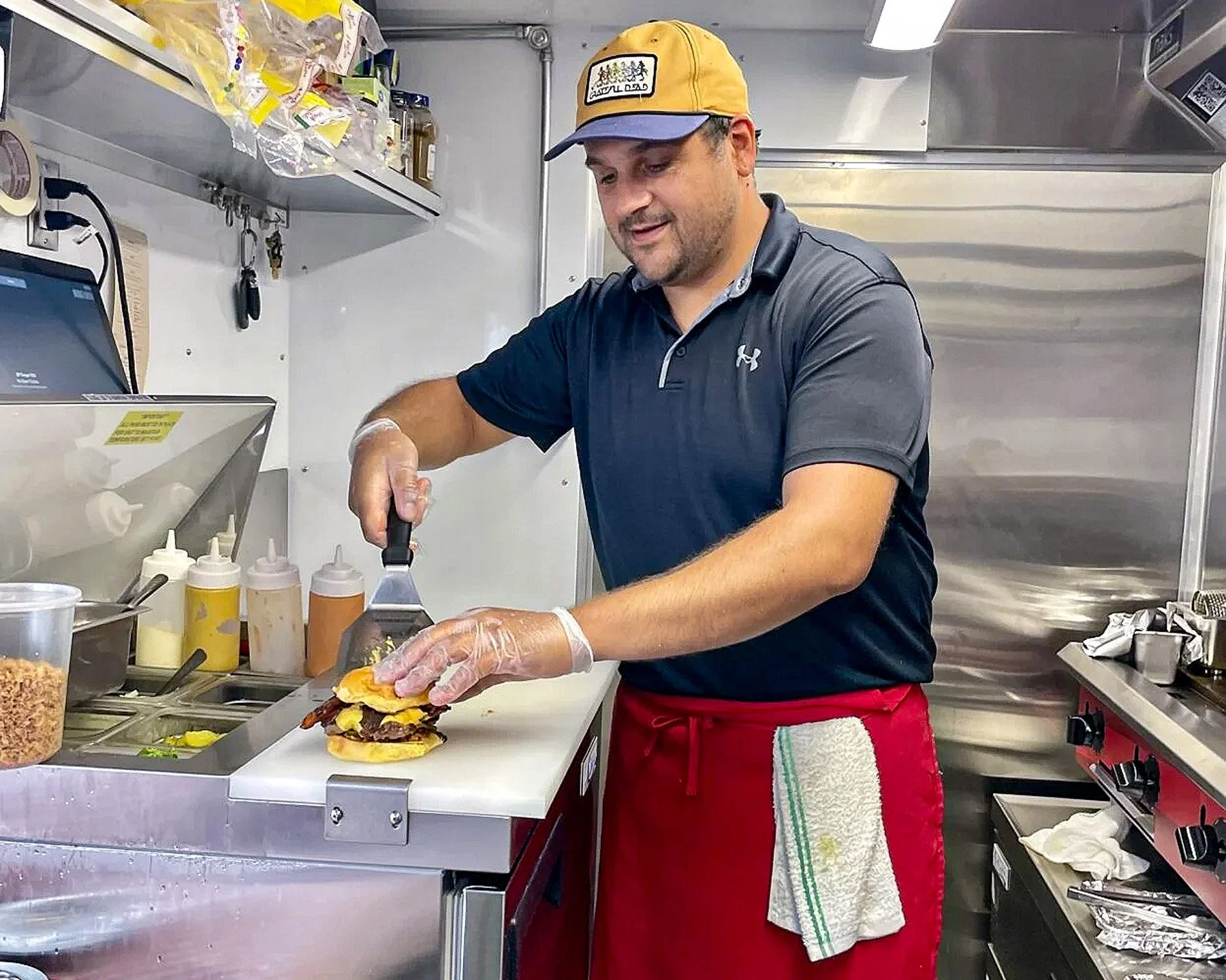 QP Burger owner Mike prepares a classic QP smash burger in the food truck in Midcoast Maine.