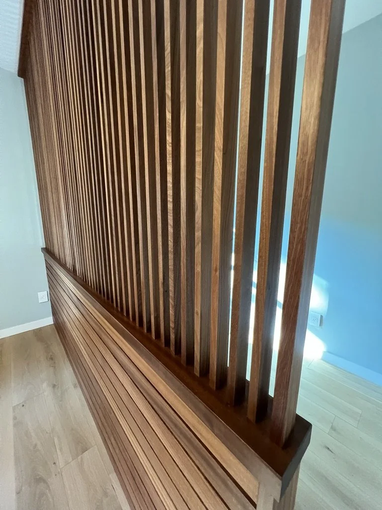 Interior view of a wooden room divider with vertical slats and a wooden bench underneath.