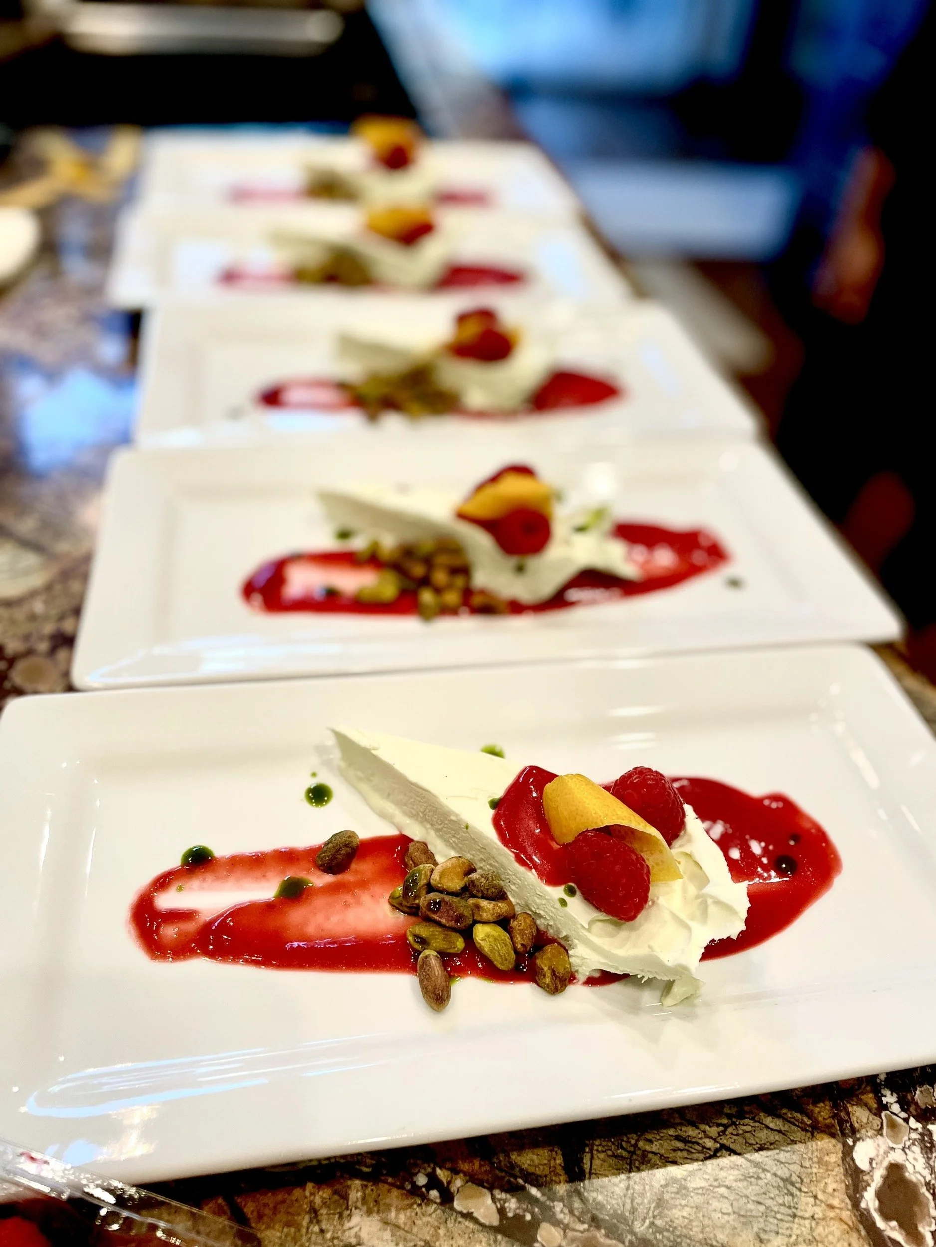 Semifreddo dessert topped with raspberry coulis, pistachios, and lemon peel.