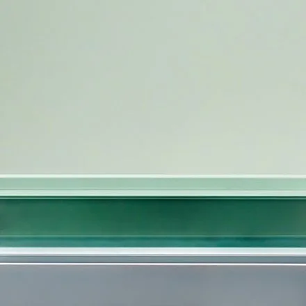 A close-up view of a green area on a textured wall with a white and gray baseboard.