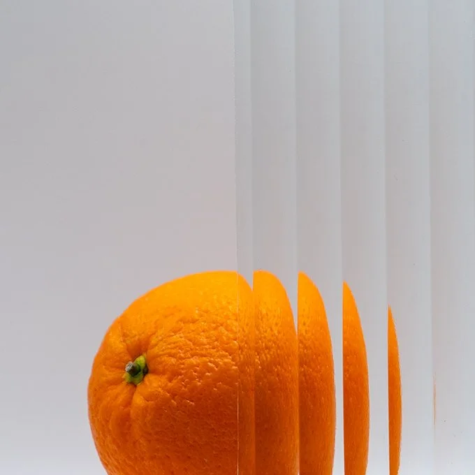 A digitally manipulated photo of an orange with mirror and split effects creating multiple images and reflections.