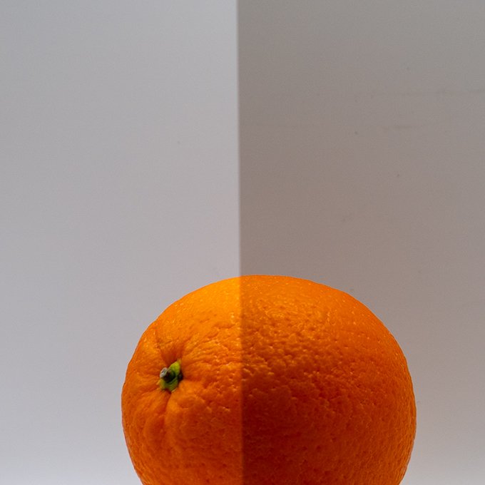 Orange lemon on a white and gray background with a split color effect.