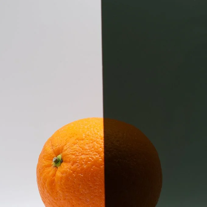 Close-up of an orange fruit split with one side against a light background and the other against a dark background.