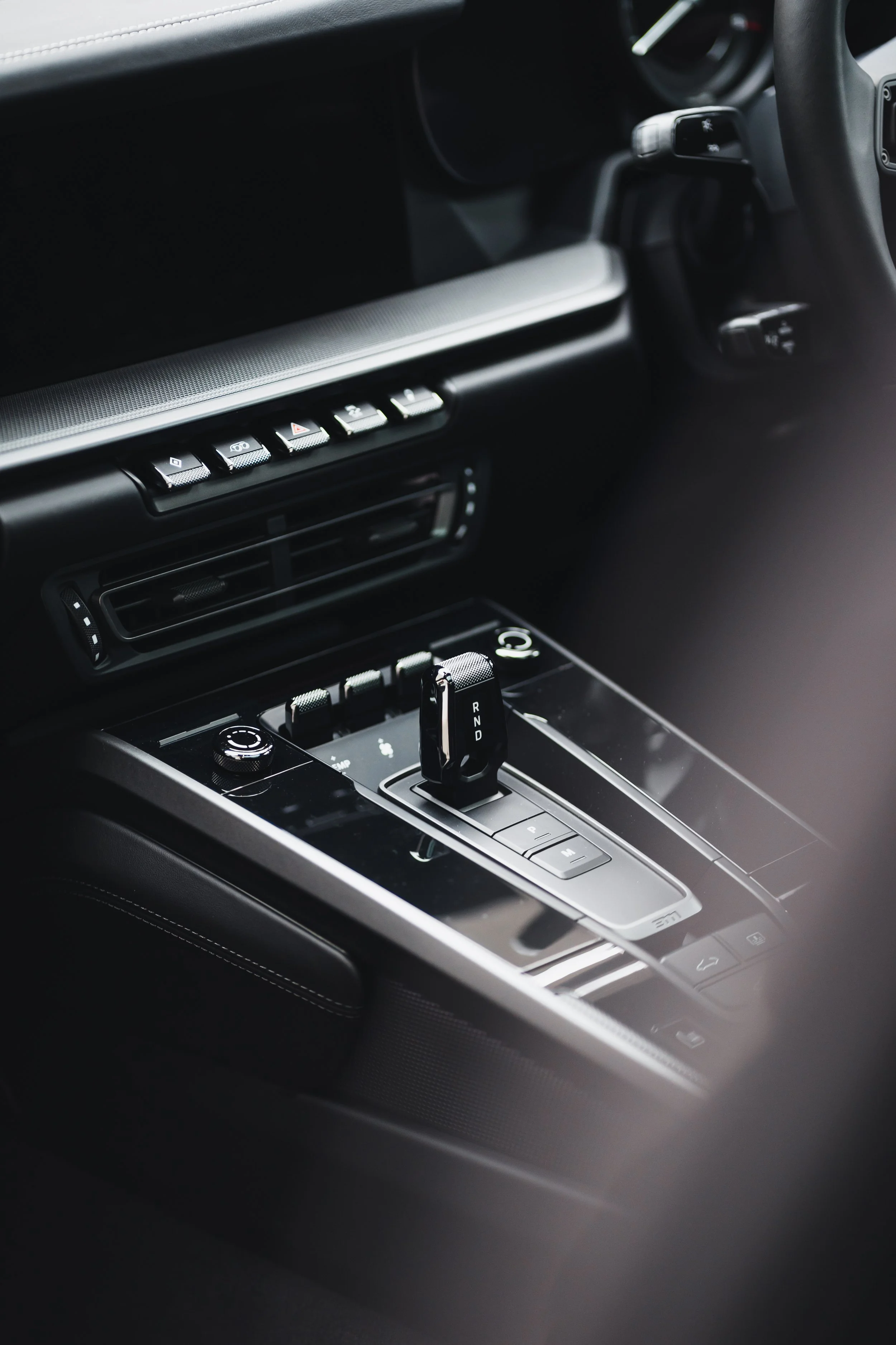 Close-up of a modern car interior showing the gear shift lever, control buttons, and air vents.