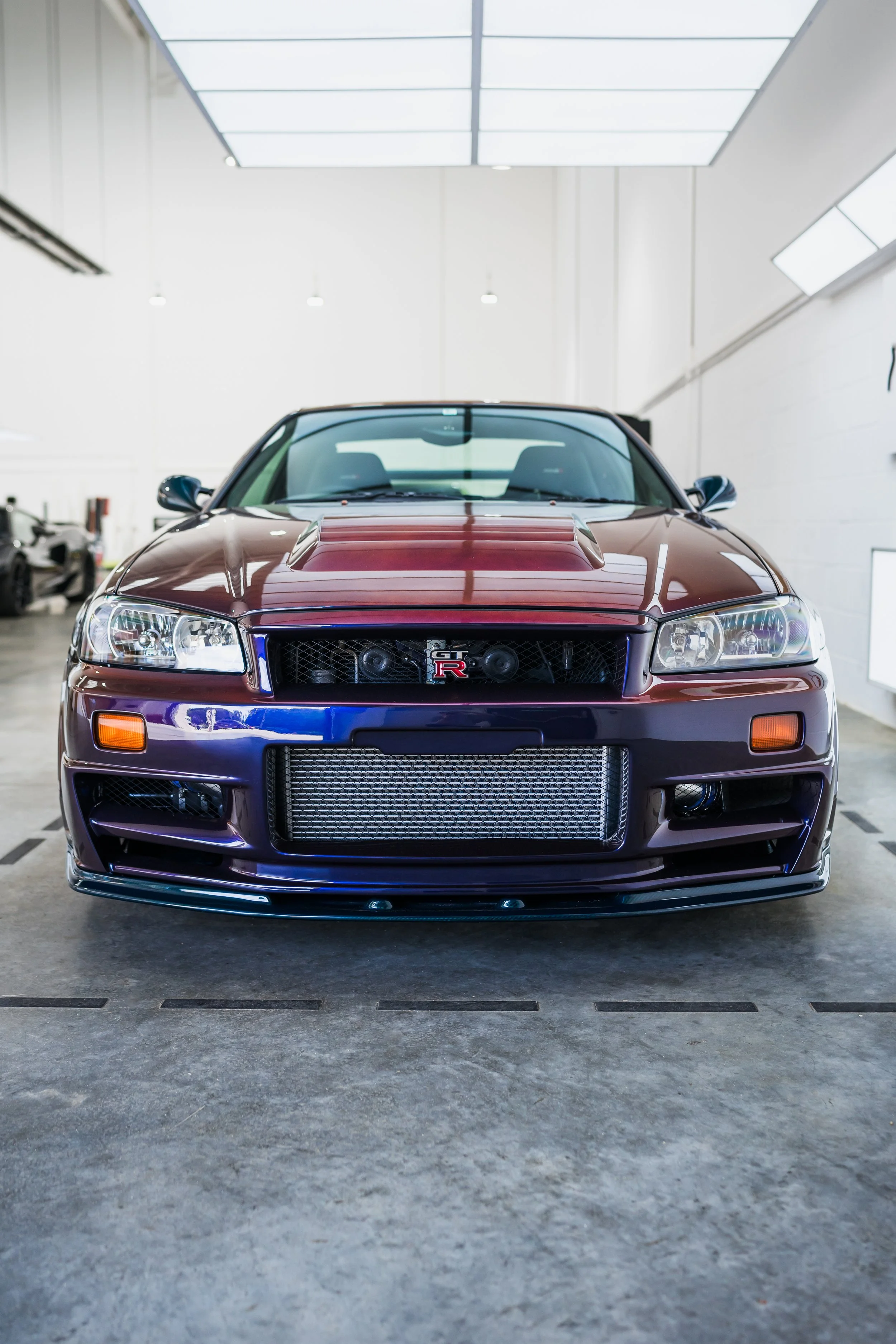 Front view of a maroon Nissan Skyline GT-R R32 sports car in a garage.