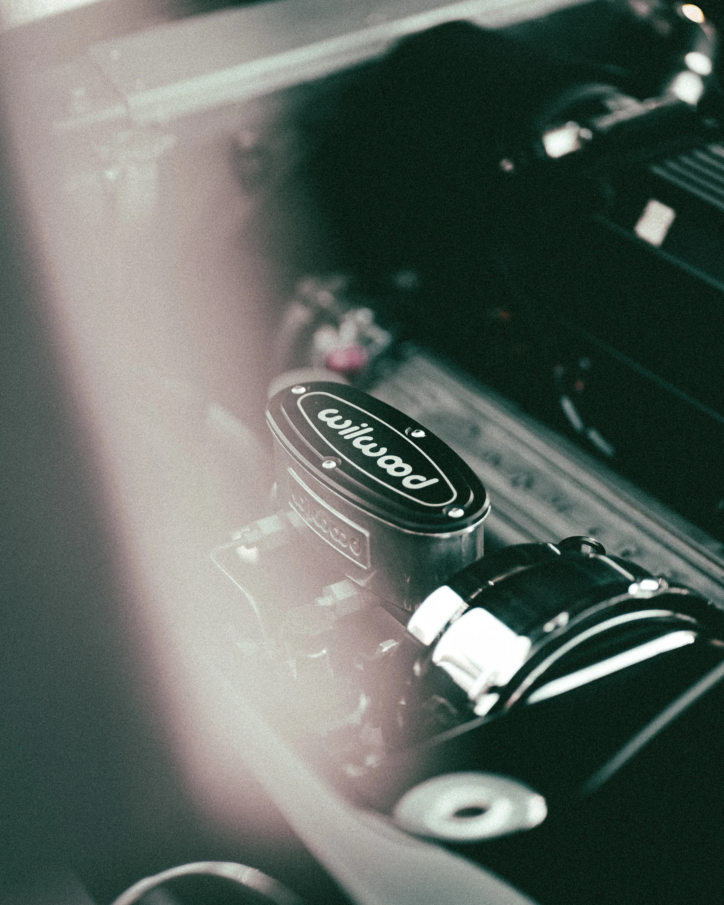 Close-up of a Wilwood brake master cylinder installed in a car engine bay.