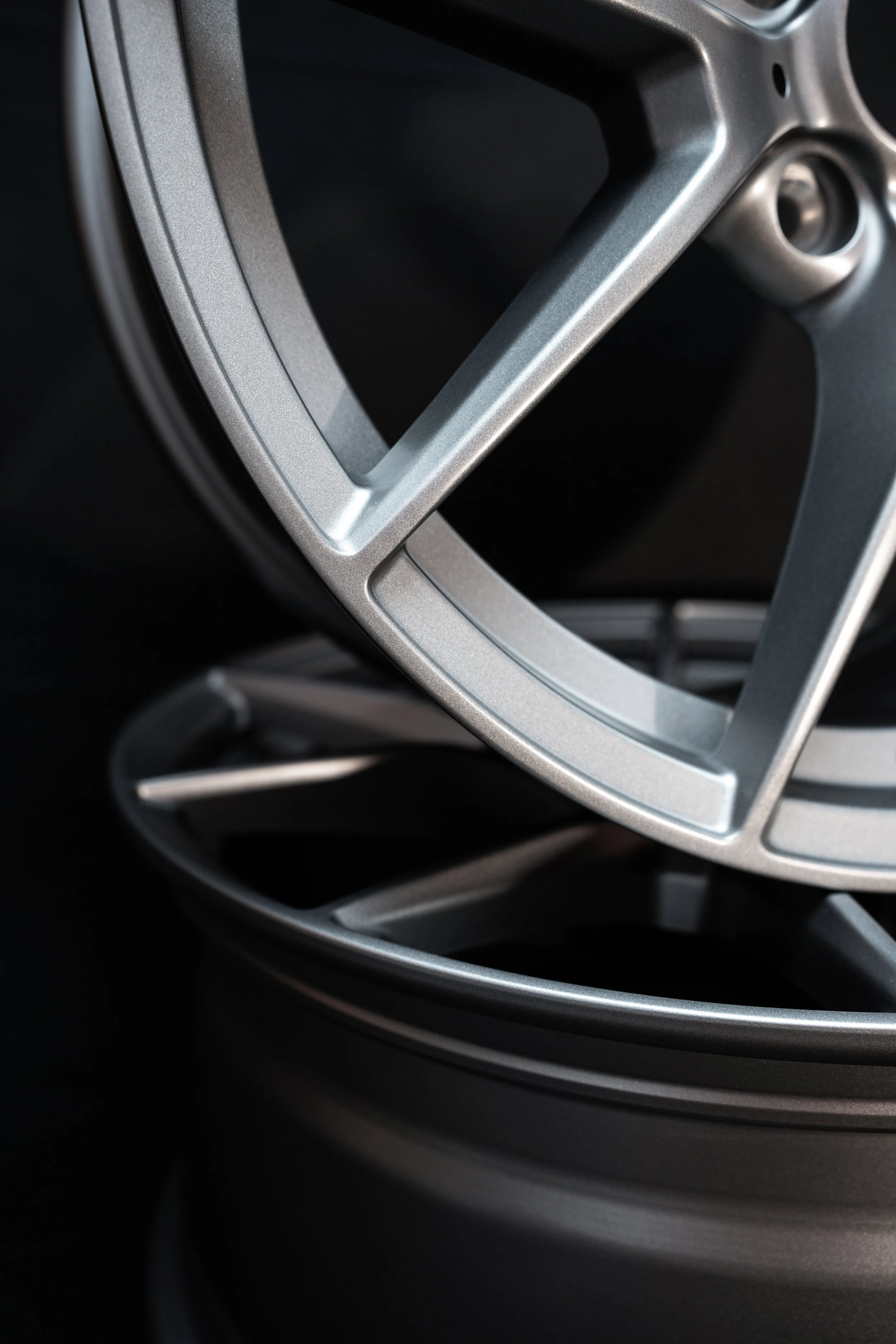 Close-up of stacked silver alloy wheels with a dark background.