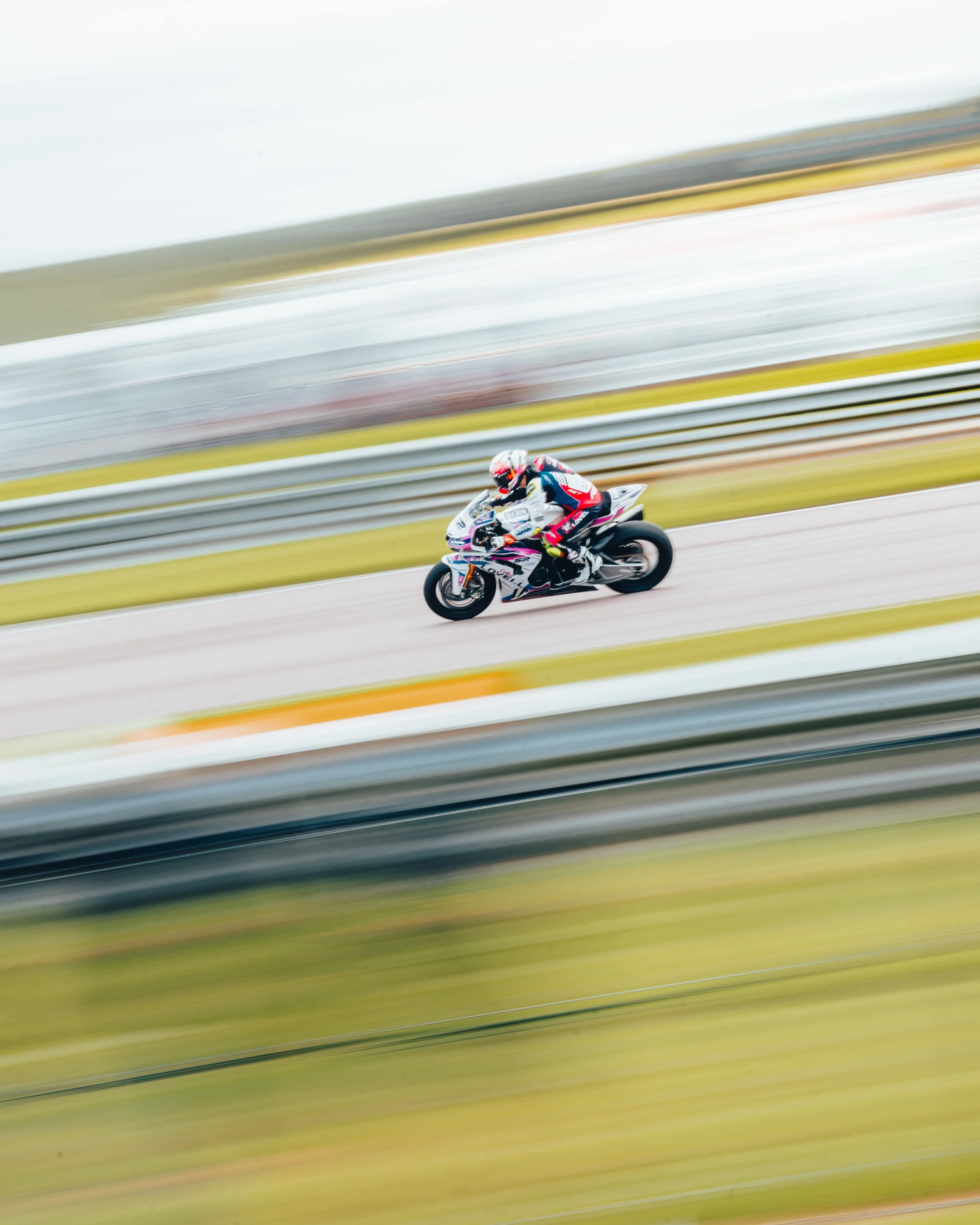 Motorcycle racer in full gear riding on a race track, motion blur background.