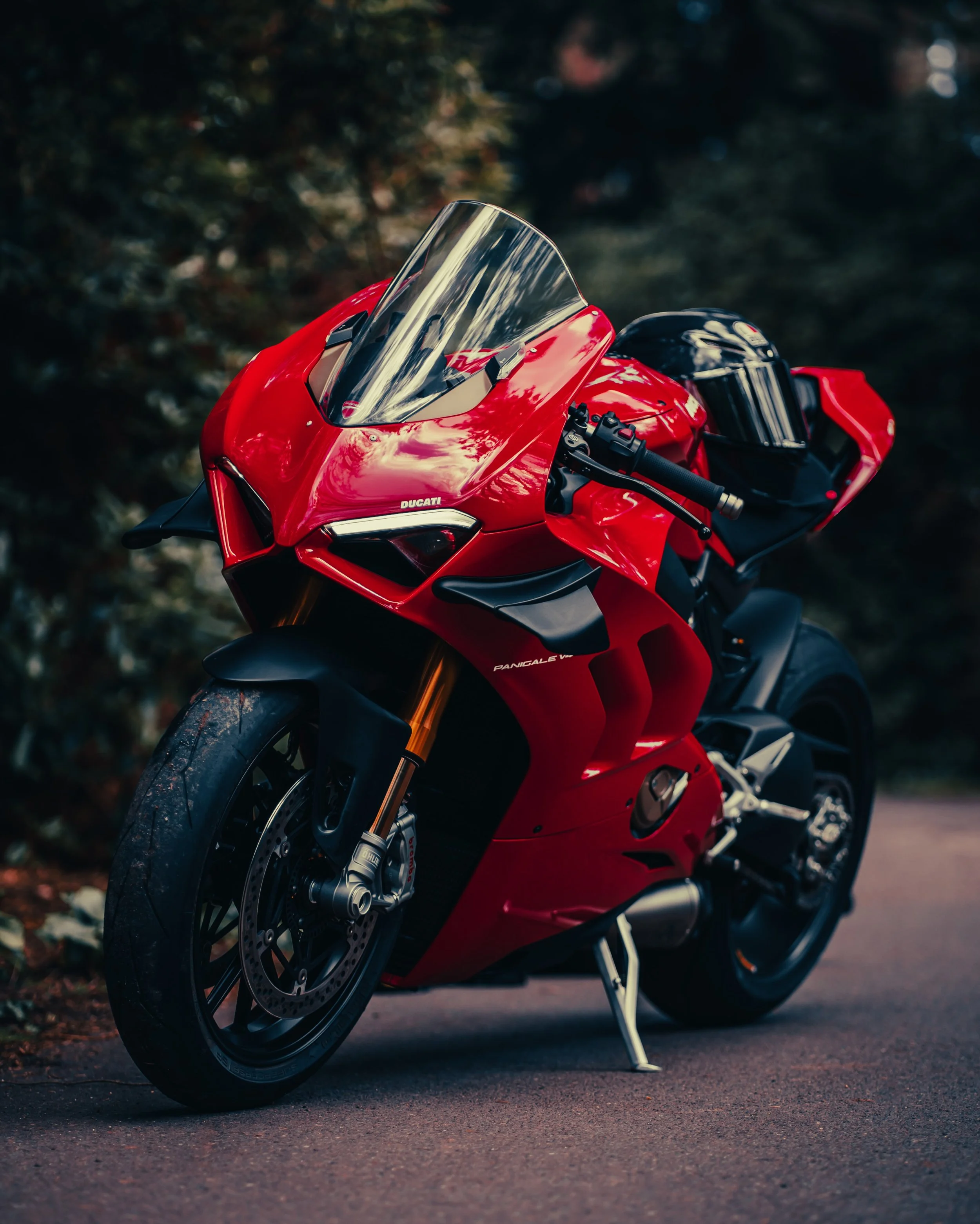 Red Ducati Panigale V4 motorcycle parked on the road with a blurred natural background.