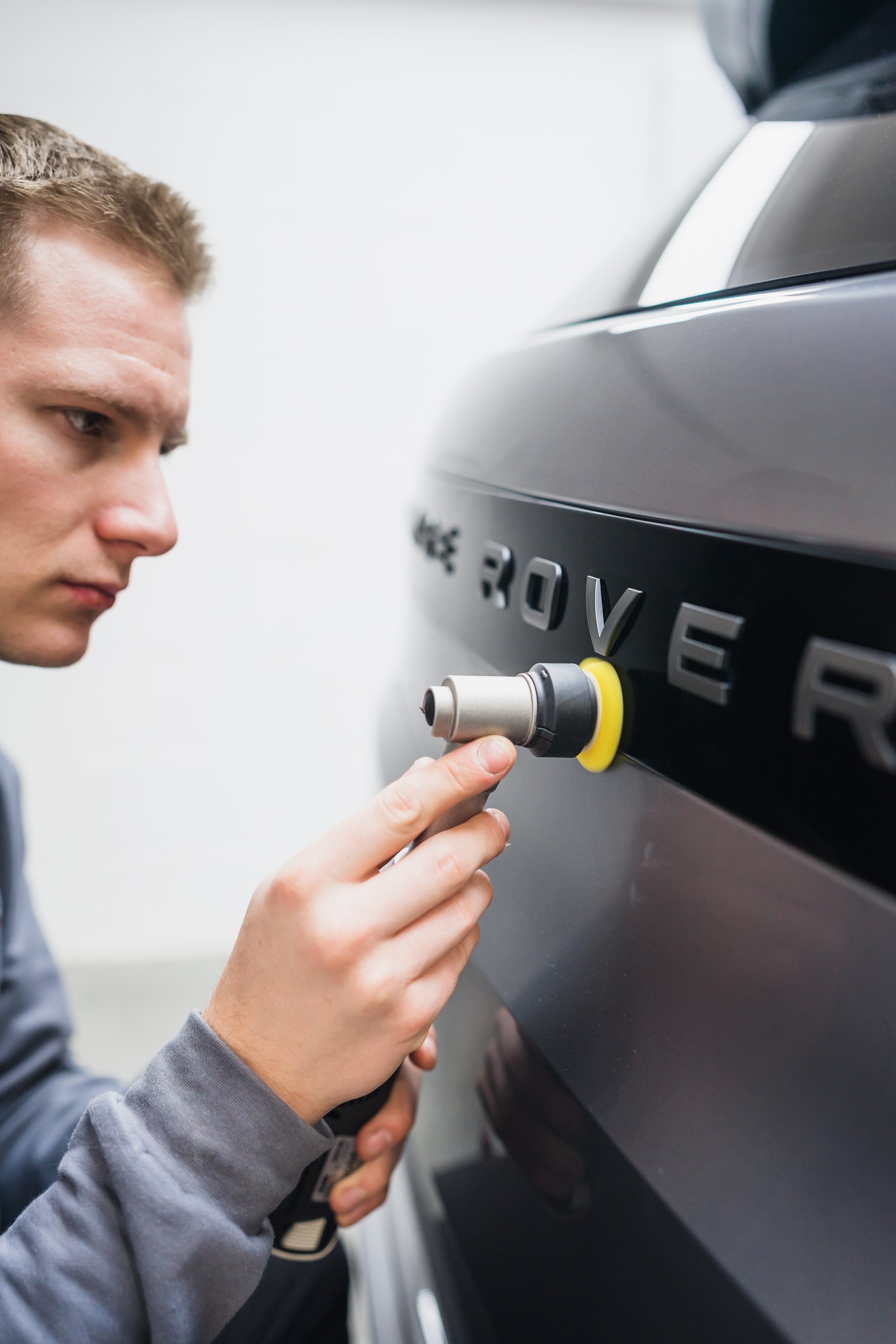 A man repairing a black Range Rover by inserting a diagnostic tool into the vehicle's port.