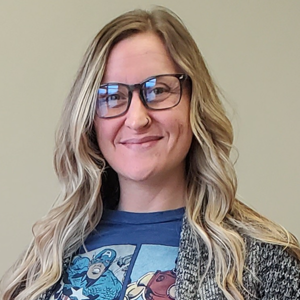 Headshot of smiling female tutor with long braids wearing a lanyard.