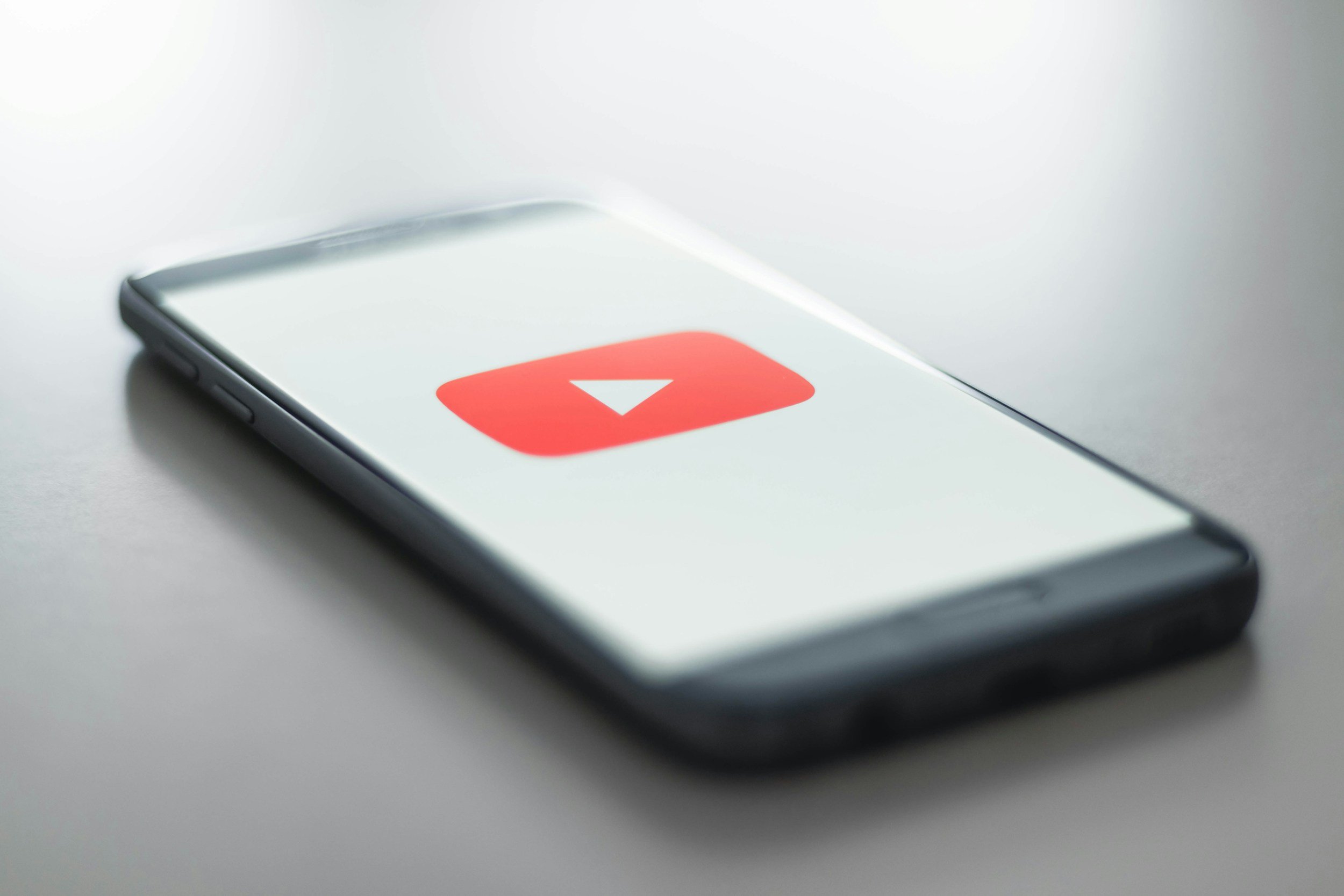 Smartphone lying on a white surface displaying the YouTube app icon.