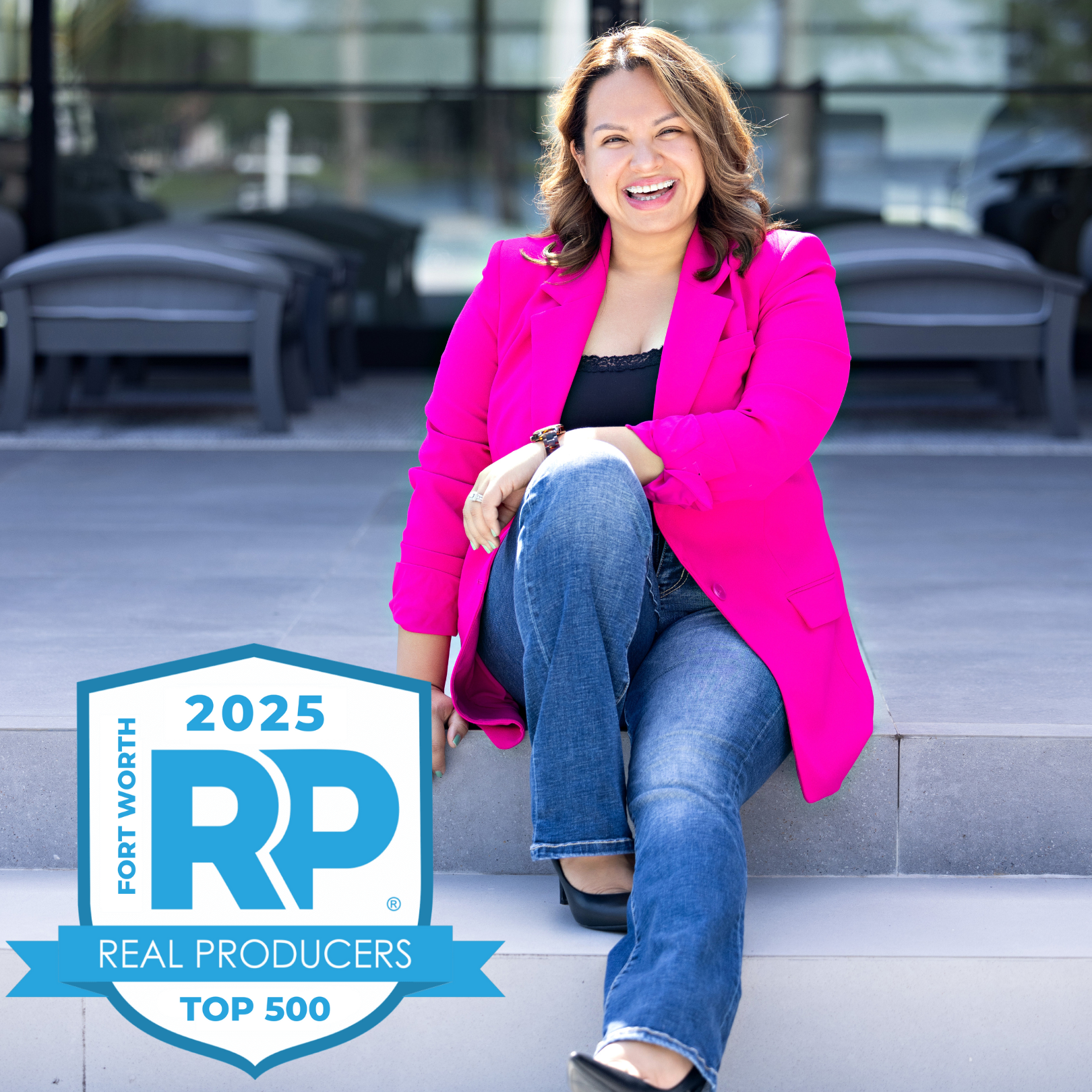 A woman sitting on outdoor steps, wearing a bright pink blazer, jeans, and black shoes, smiling. A logo for the 2025 Fort Worth Real Producers Top 500 is visible in the bottom left corner.