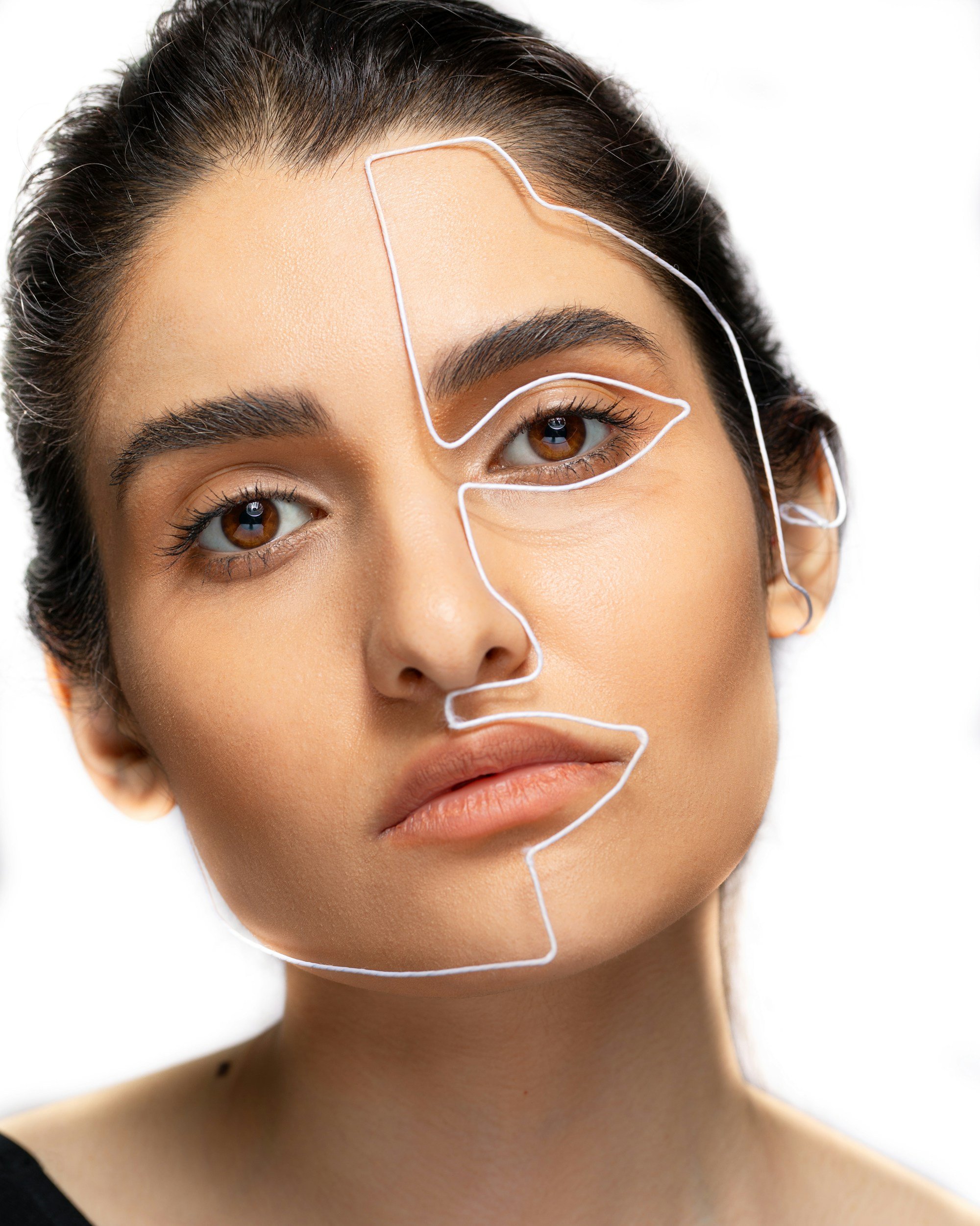 A woman with brown hair and brown eyes has a white skin patch on her face, outlined by a white wire frame.