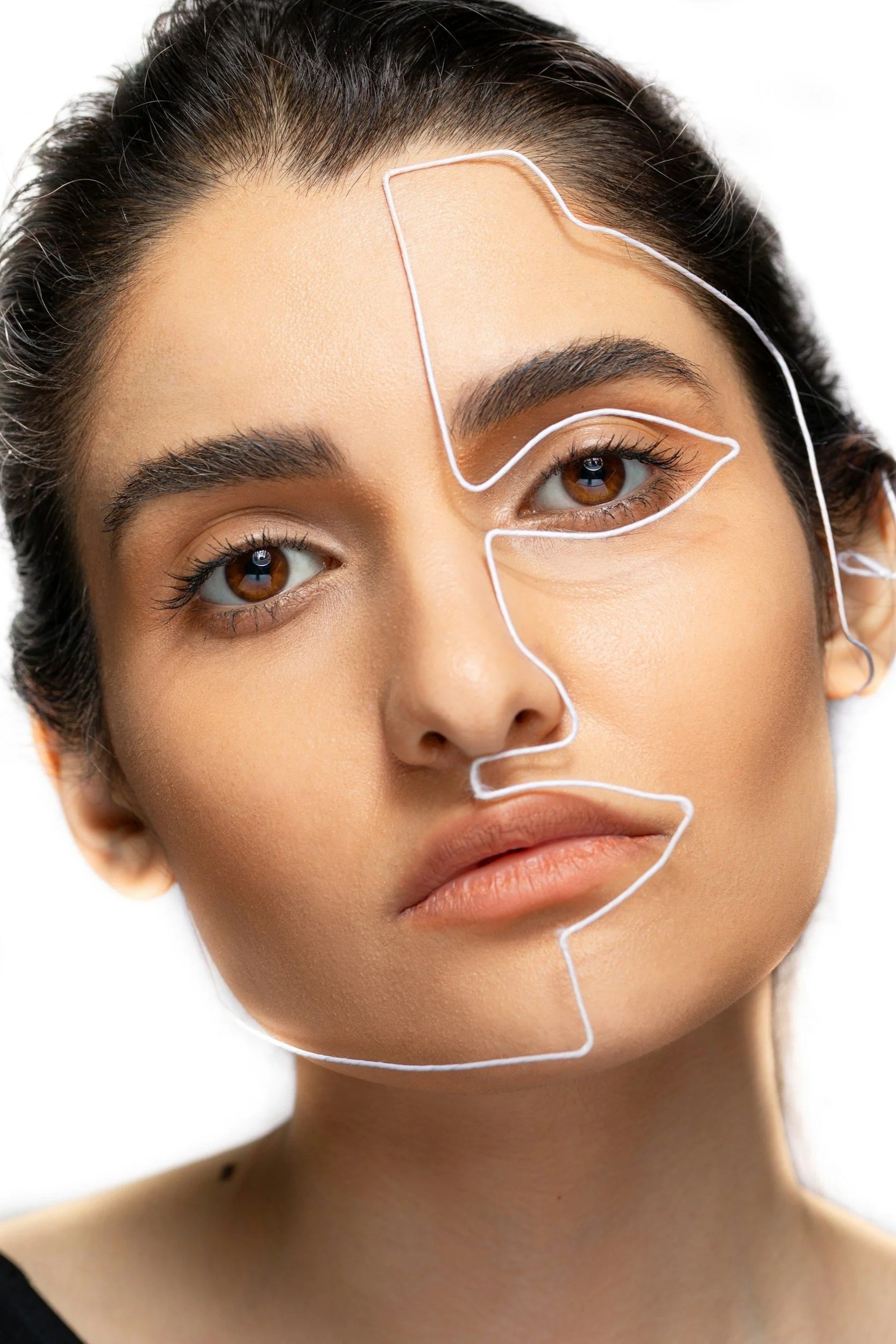 Close-up of a woman's face with a white outline highlighting her facial features and a wireframe overlay on her forehead and eye area.