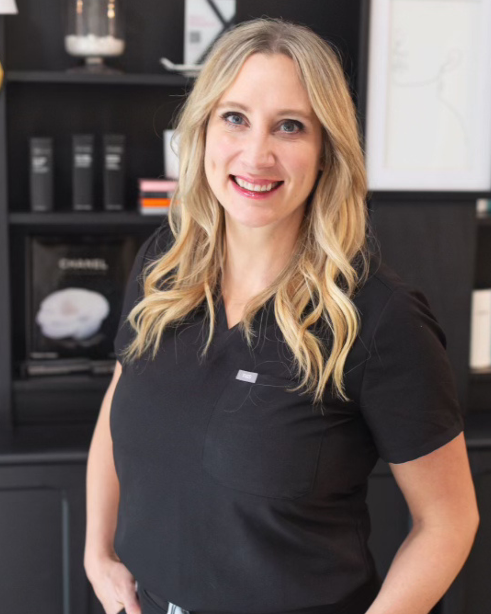 A woman with long blonde hair smiling in an office or professional setting.