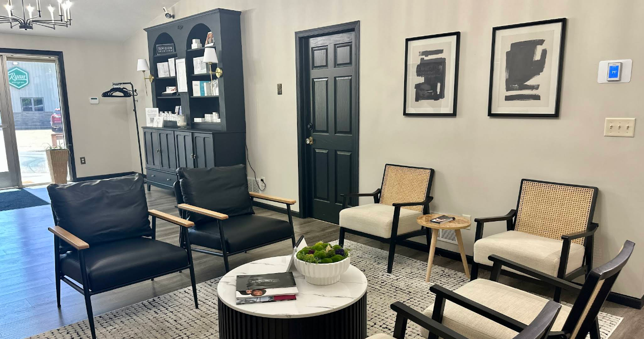 Living room with black and white chairs, a white marble coffee table, wall art, and a bookshelf.