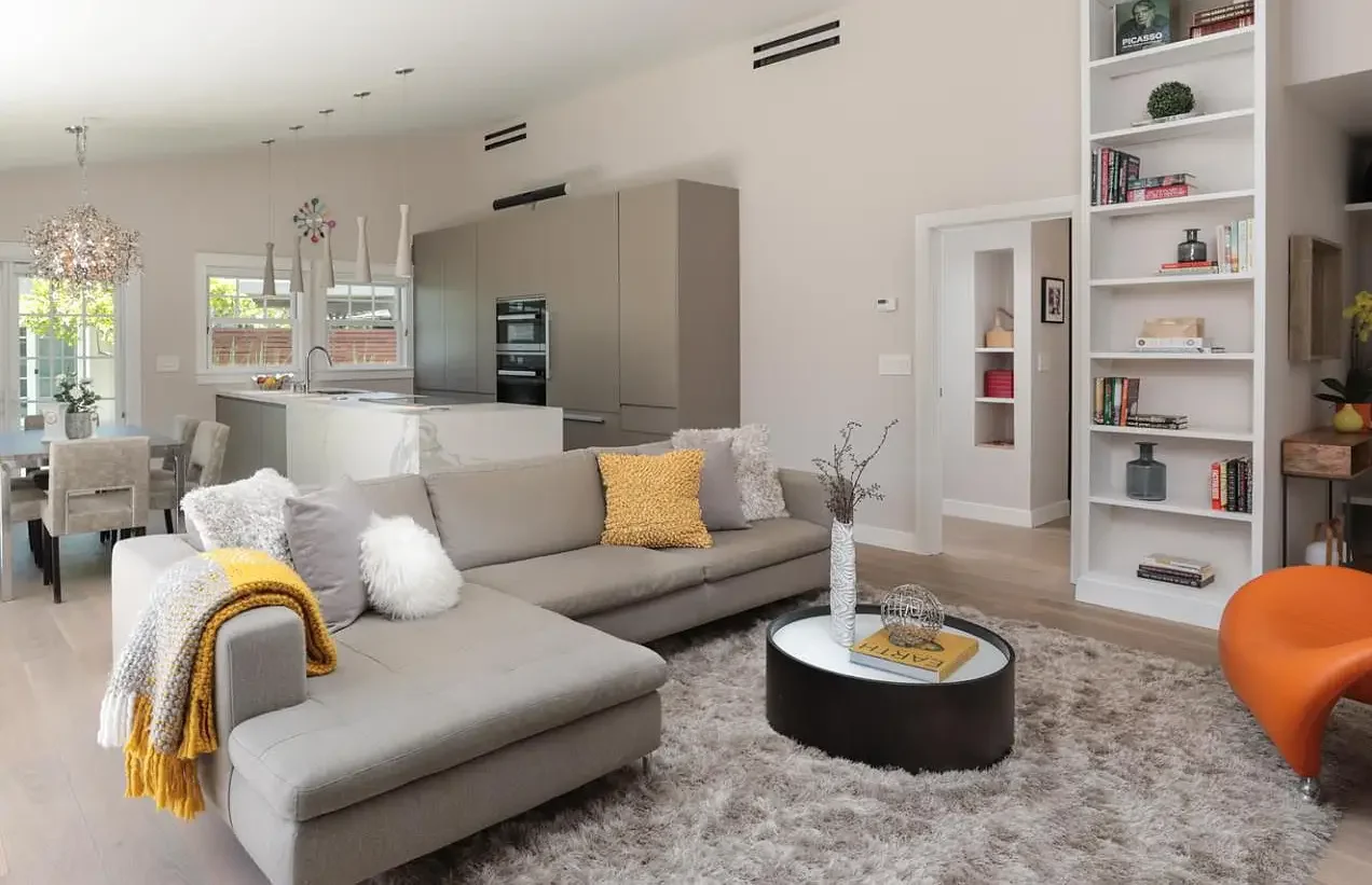 Modern kitchen with large island, pendant lights, and sliding glass door leading to patio with outdoor furniture.