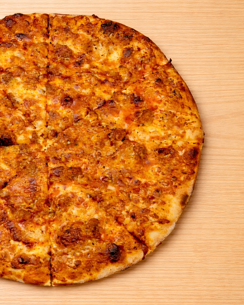 A whole pepperoni pizza with cheese and toppings on a wooden surface, partially sliced.