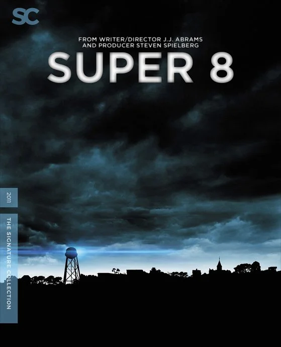 Cover of a film titled "Super 8" with a dark, cloudy sky and a silhouette of a small town with a water tower.
