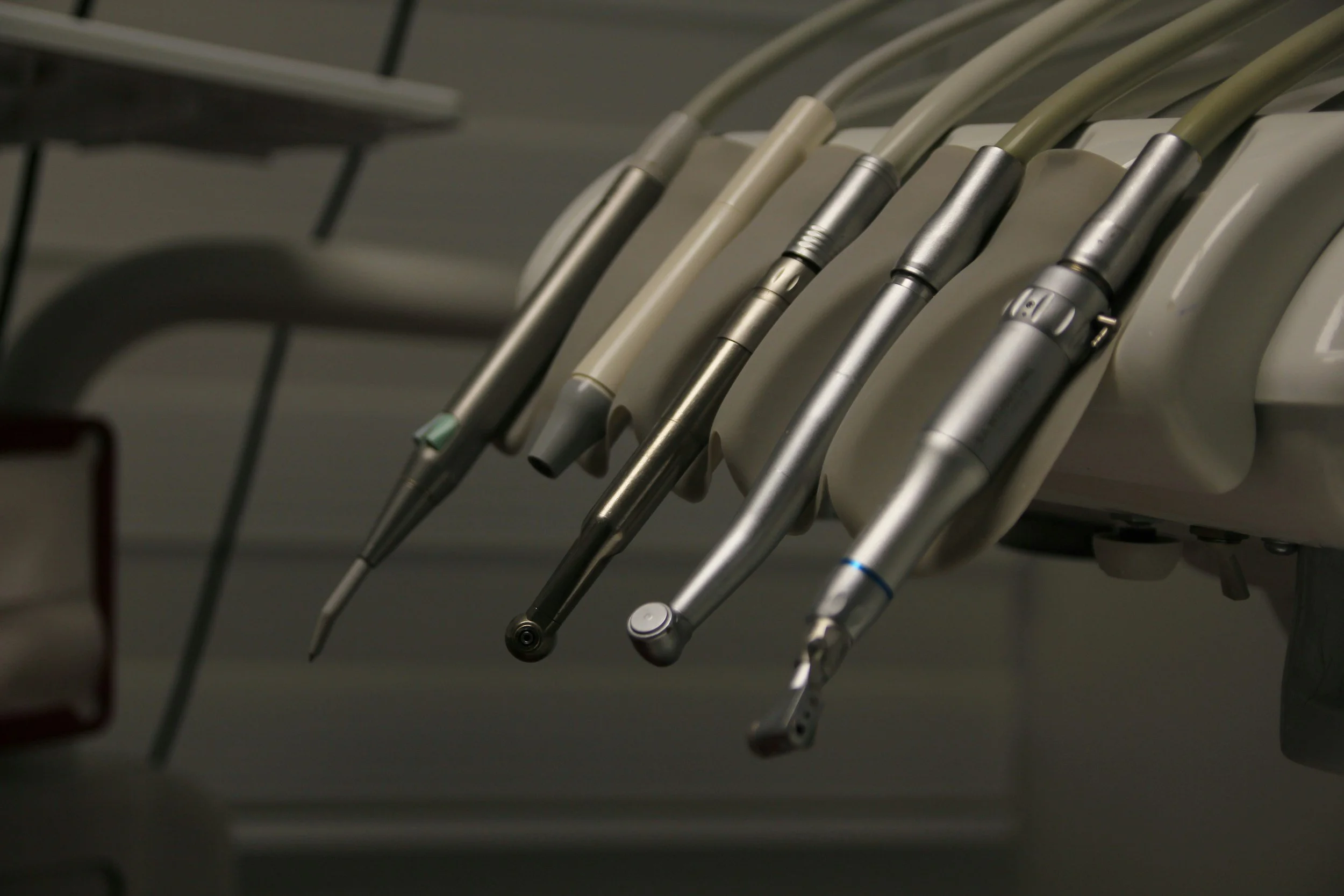 A row of dental tools hanging on a tray in a dental clinic.