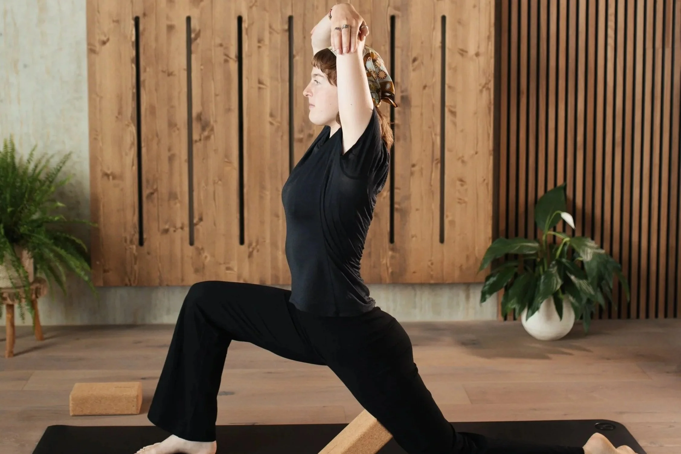 Woman practicing  yoga in a studio in a low lunge pose with the support of cork yoga blocks
