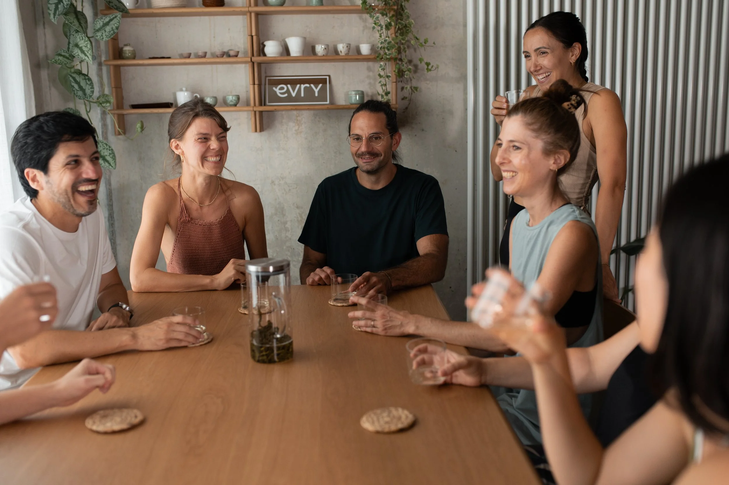 A group of friends sit at a table drinking tea and laughing together during a team event at evry yoga in Zurich