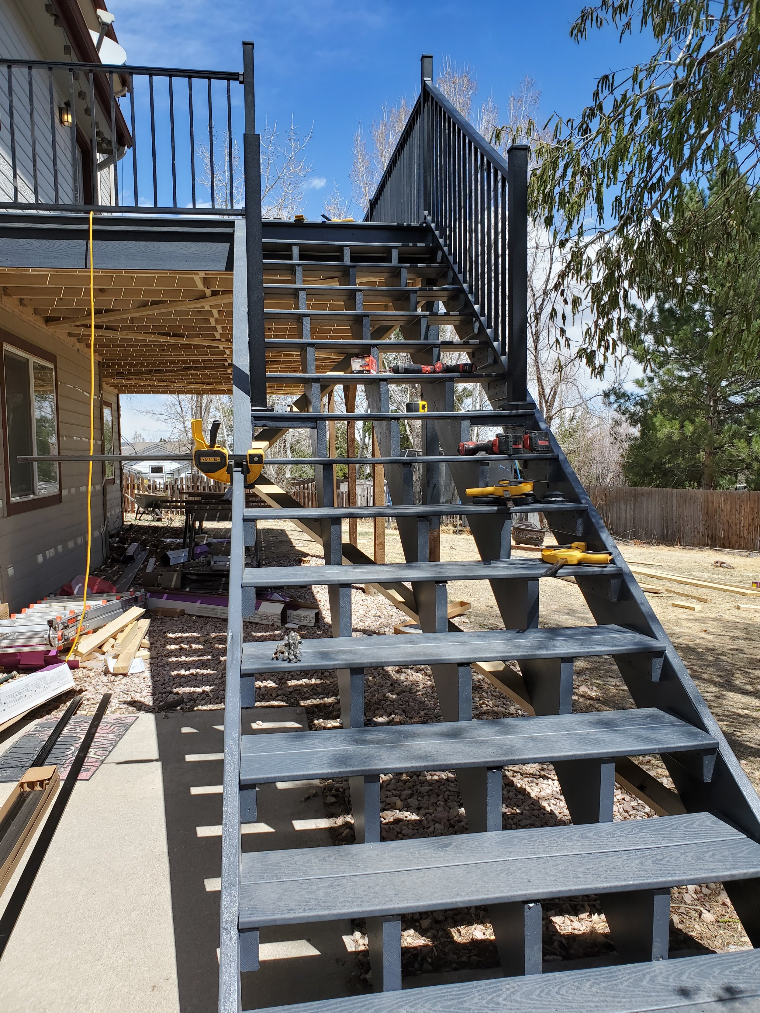 Construction of an outdoor staircase attached to a house with tools and materials on the steps and ground.