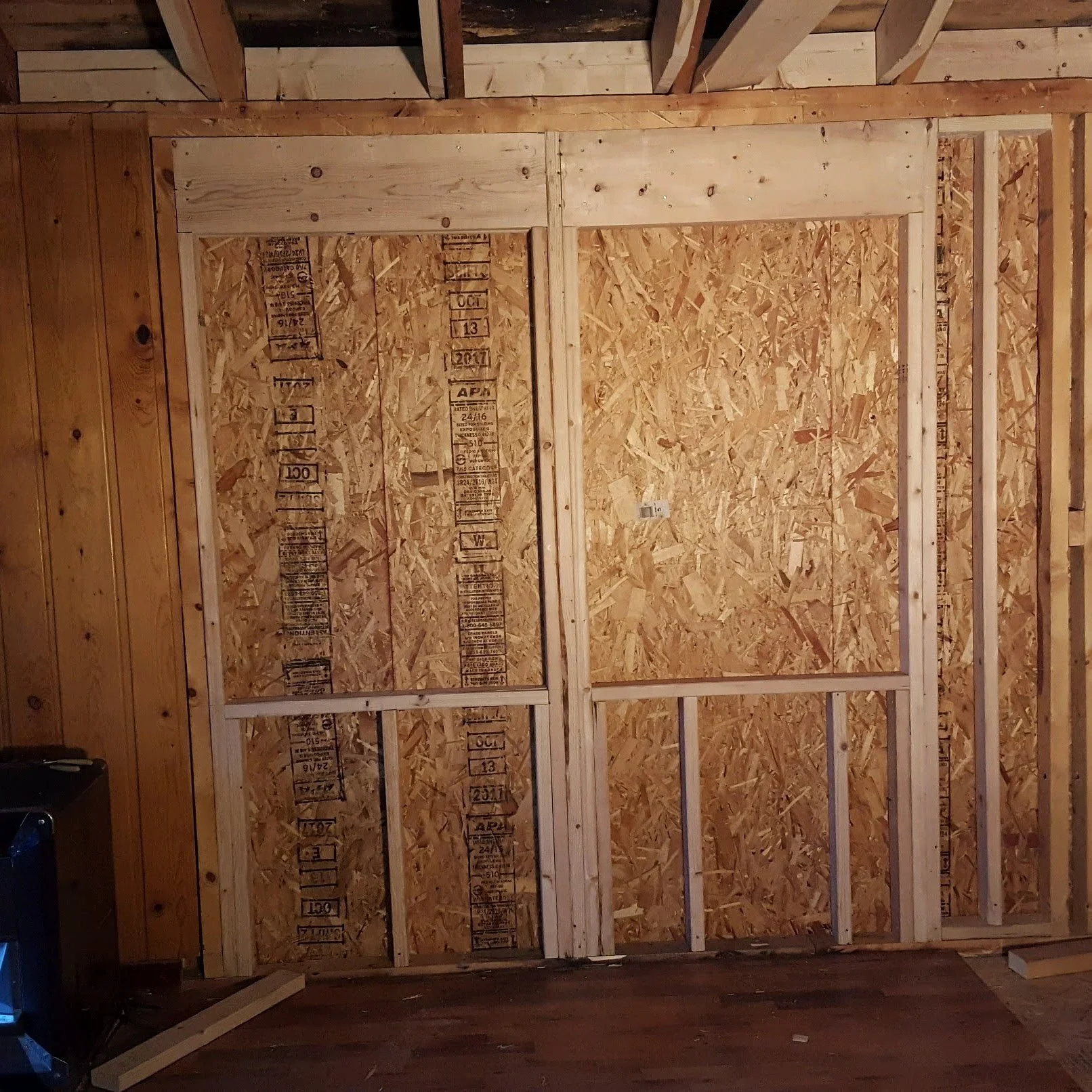 Interior of a building under construction with unfinished wooden framing and wall sheathing.