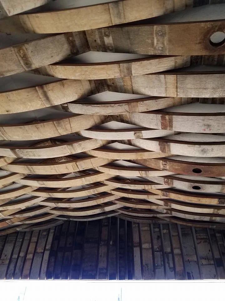 Wooden boat racks installed on a ceiling in an unfinished building.