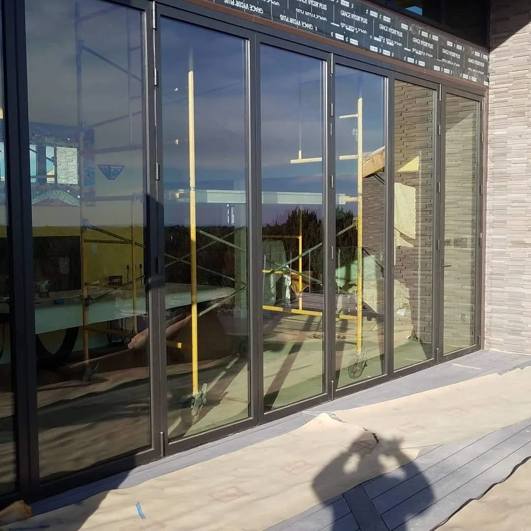 A glass sliding door with reflective surface, showing construction scaffolding and outdoor scenery.