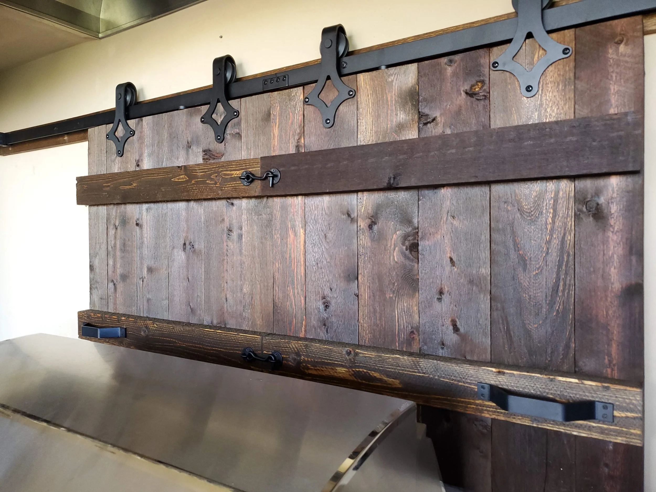 A sliding barn door with several wooden planks, metal hardware, and roller guides, mounted on a wall.