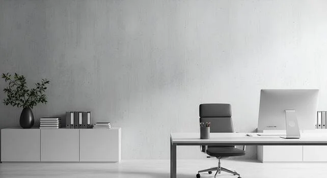 Modern minimalist office with white desk, black chair, and white storage cabinet with black vase and stacked books
