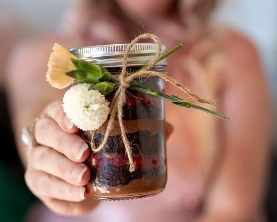 Three mason jar desserts layered with cake and buttercream cream, topped with colorful sprinkles.