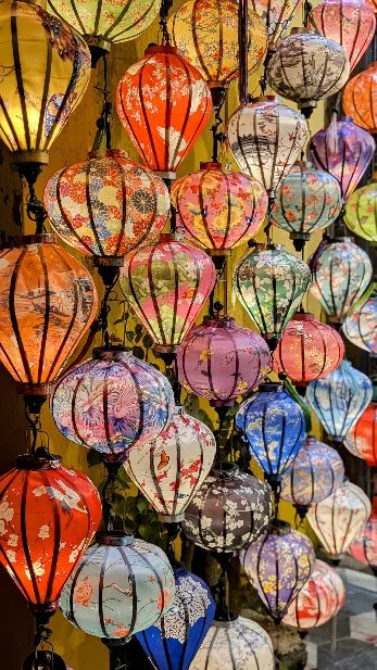 Colorful paper lanterns hanging in a display, featuring various patterns and colors including red, orange, yellow, green, blue, purple, and white.