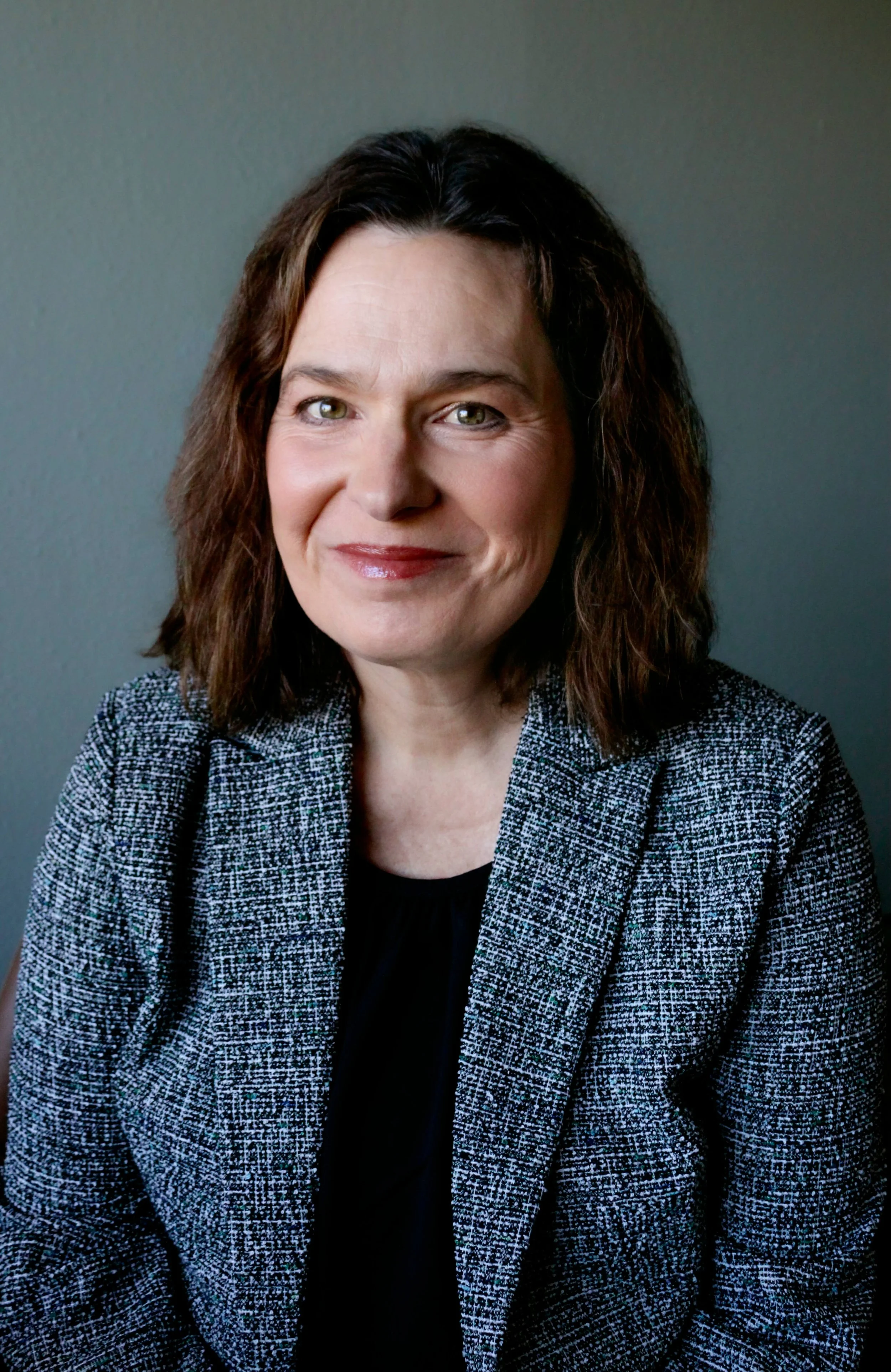 Dr. Renee Woodall, therapist in Fort Collins, CO, wearing a black top and a gray blazer, against a plain gray background.