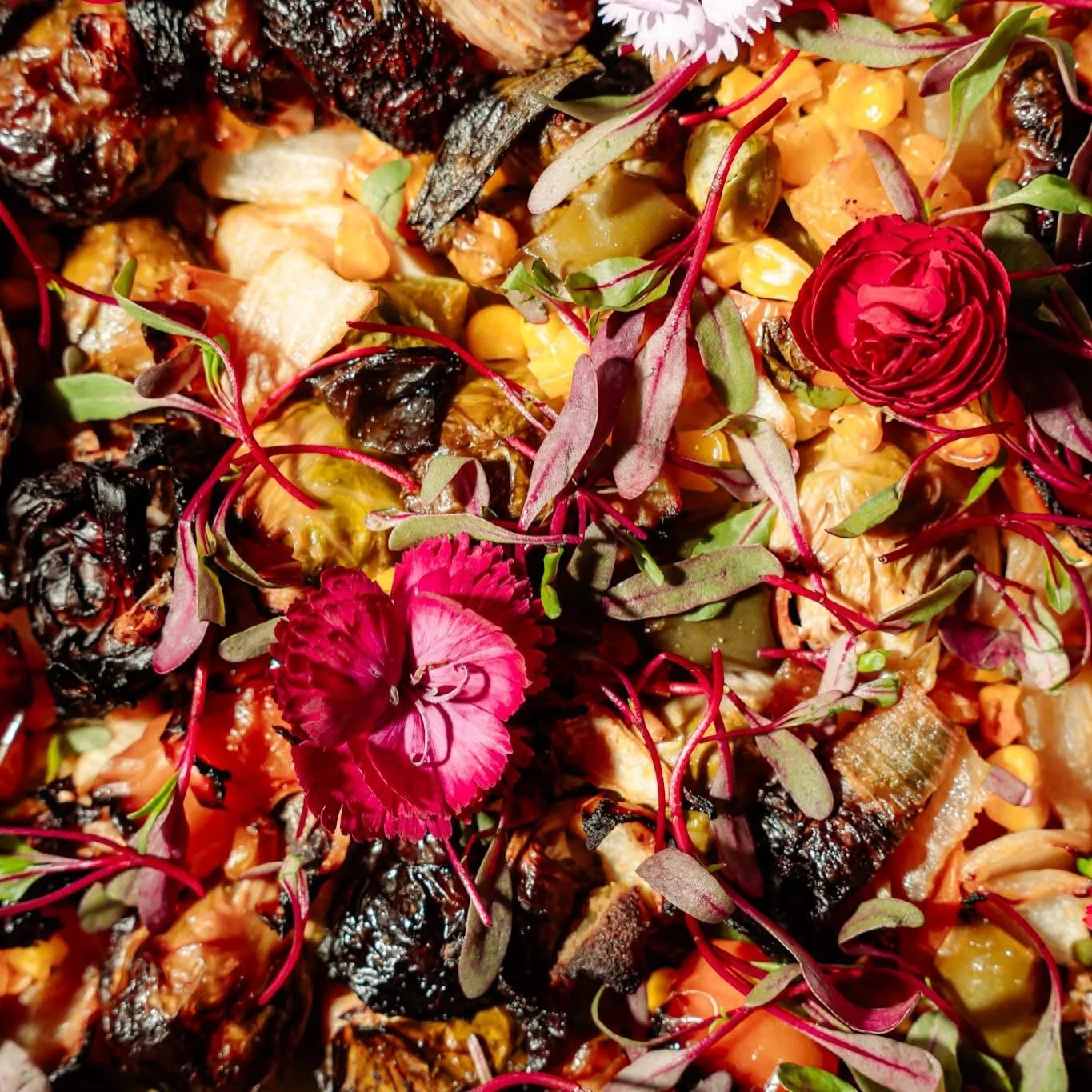 Close-up of a colorful salad with grilled vegetables, greens, and edible flowers.