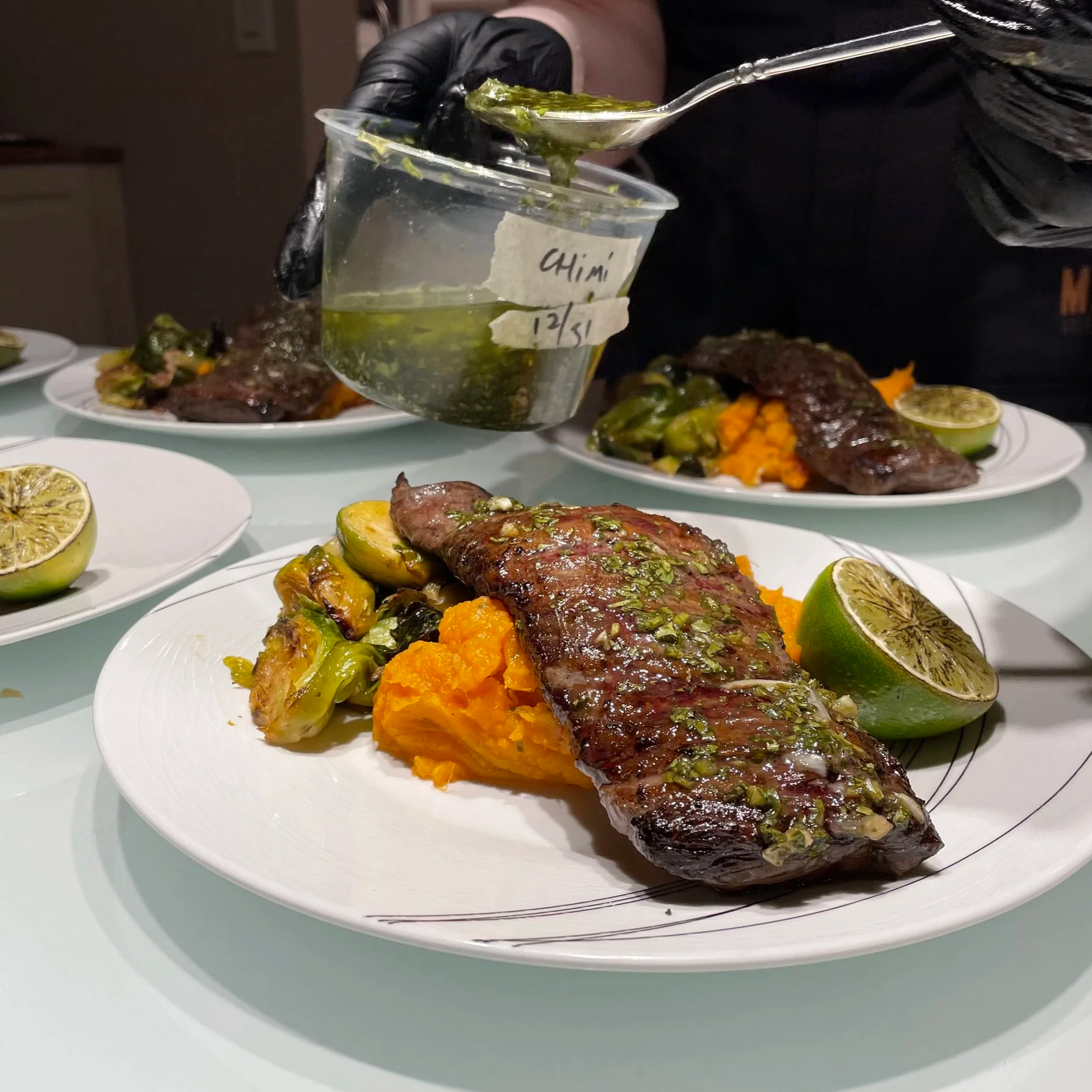 Photo of Chef Jessica plating up steak chimichurri with brussels sprouts and pureed sweet potato