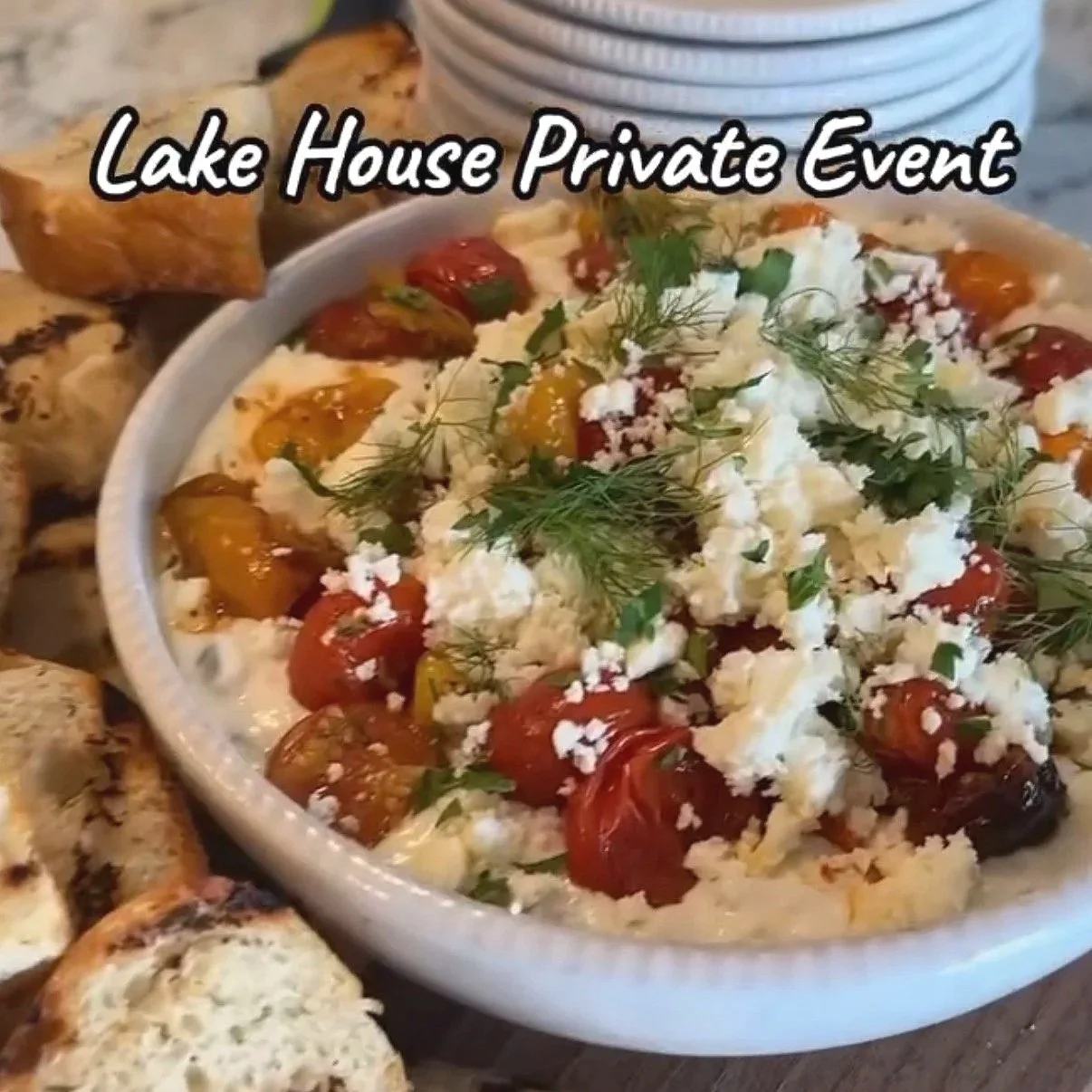 Bowl of tomatoes, feta, dill and other dip with grilled bread beside it. The words Lake House Private Event typed on top of photo