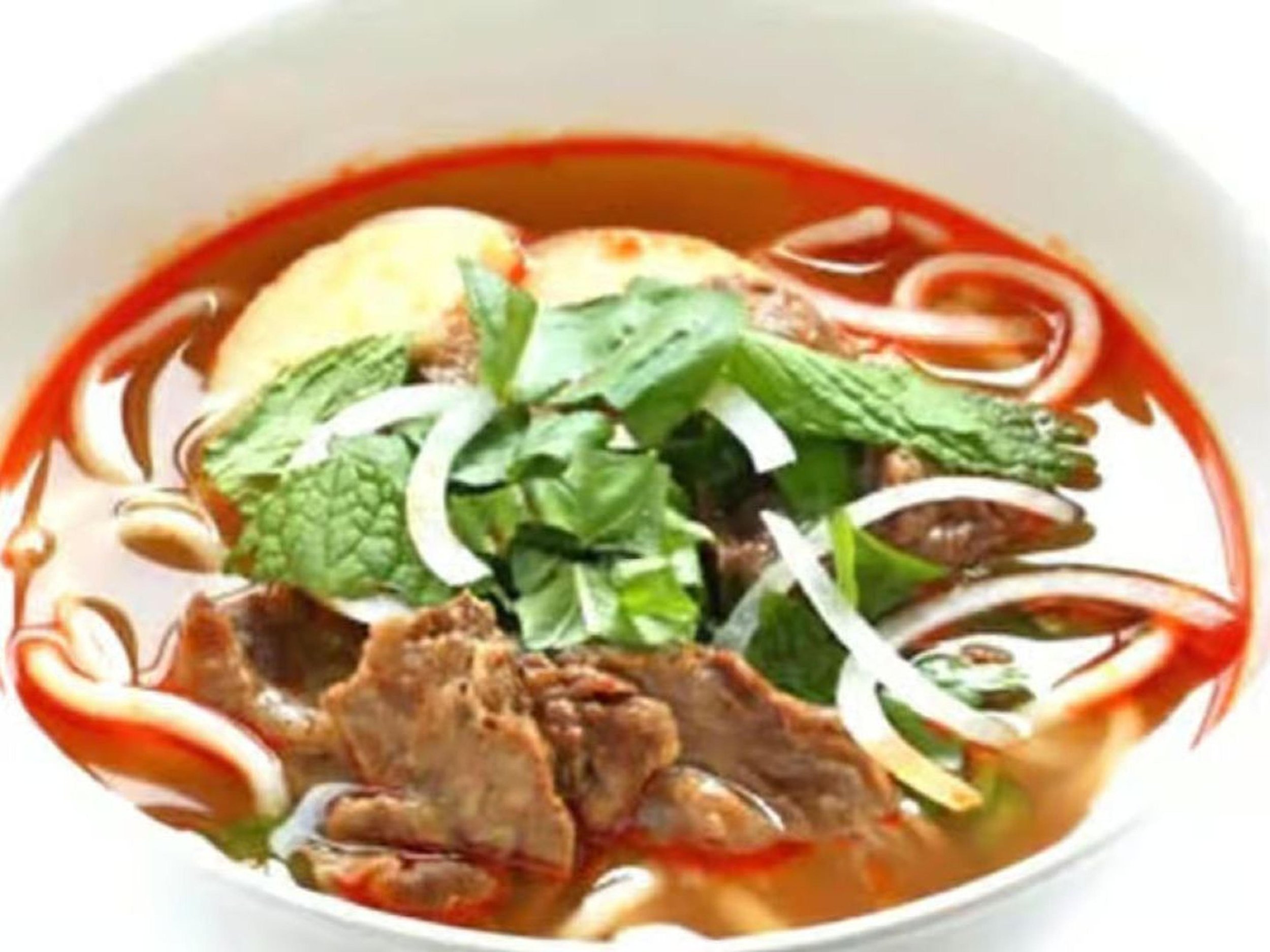 Bowl of Vietnamese pho with beef, rice noodles, topped with fresh herbs, onions, and green onions.