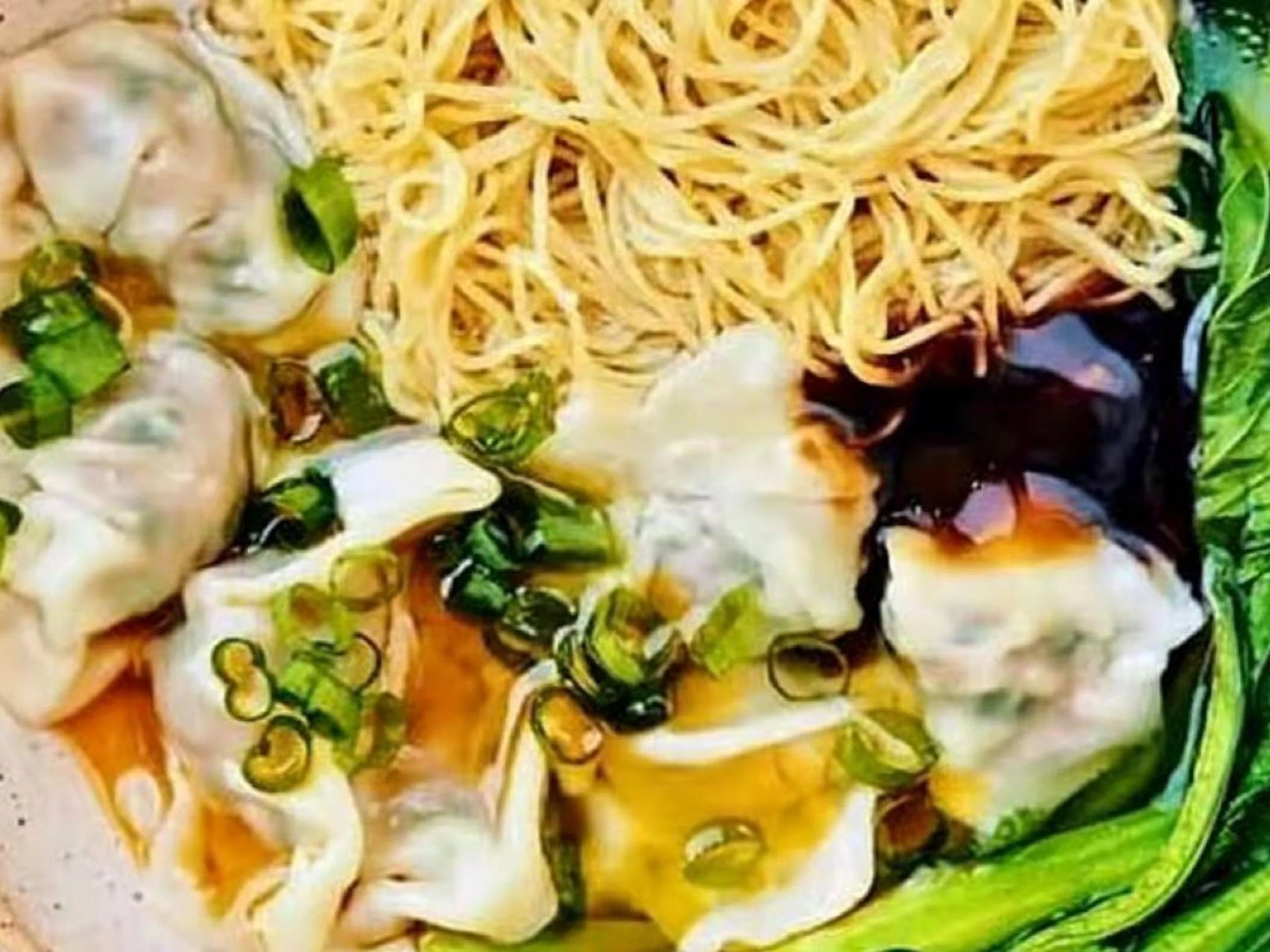 Close-up of a bowl of ramen with noodles, sliced green onions, mushrooms, seaweed, and broth.