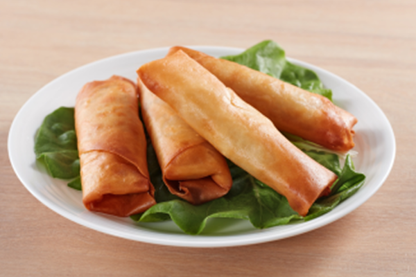 Four spring rolls on a white plate garnished with lettuce leaves.