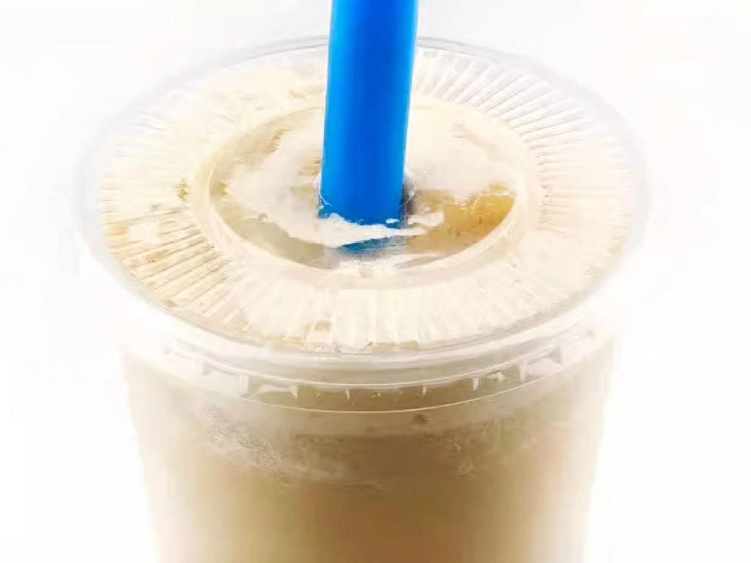 Close-up of a plastic cup filled with a light brown iced beverage with a blue straw, seen from above, with a clear plastic lid.