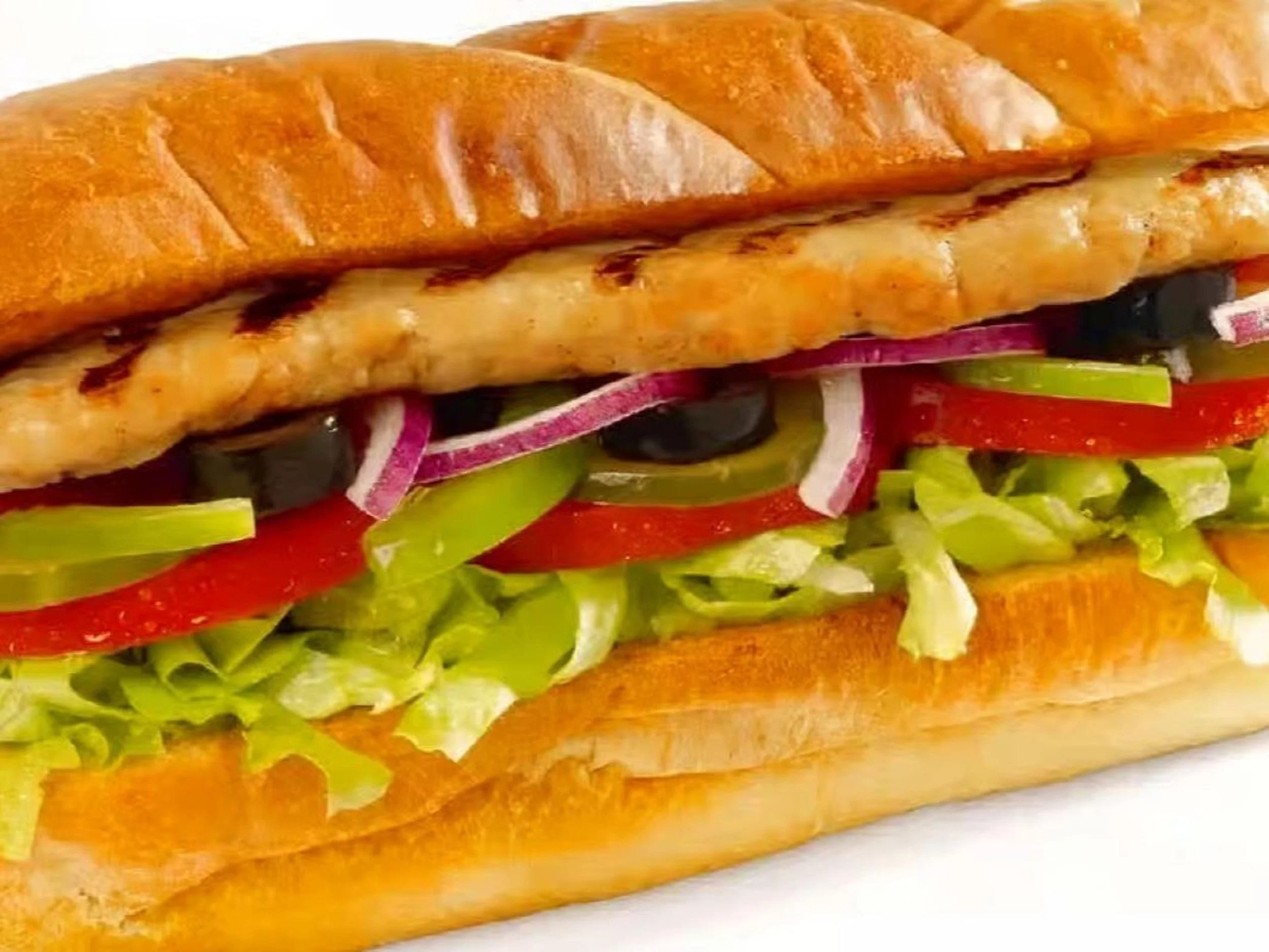 Close-up of a submarine sandwich with grilled bread, lettuce, tomato, red onion, green pepper, black olives, and grilled chicken.