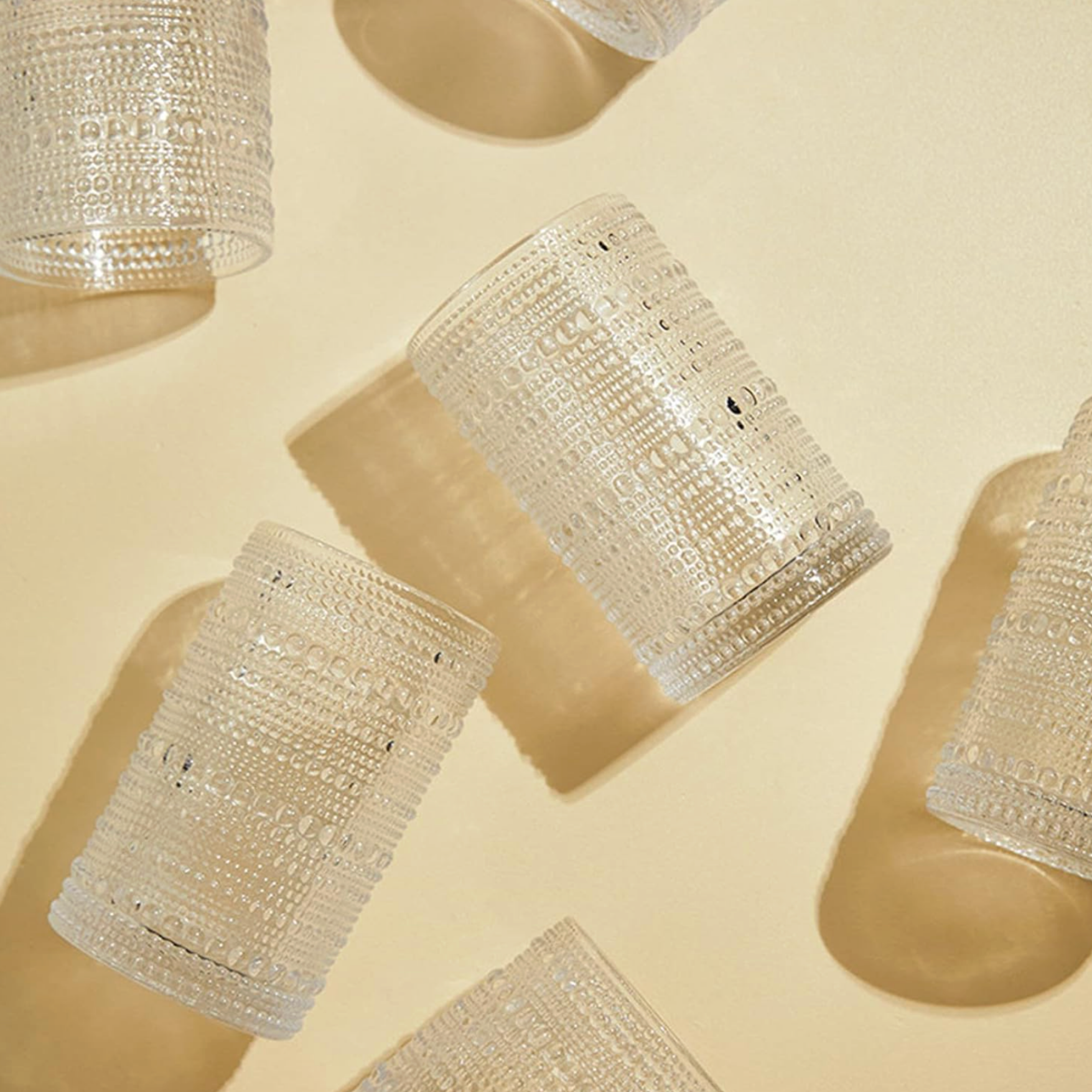 Multiple transparent cylindrical objects with intricate dotted patterns, arranged on a light-colored surface.