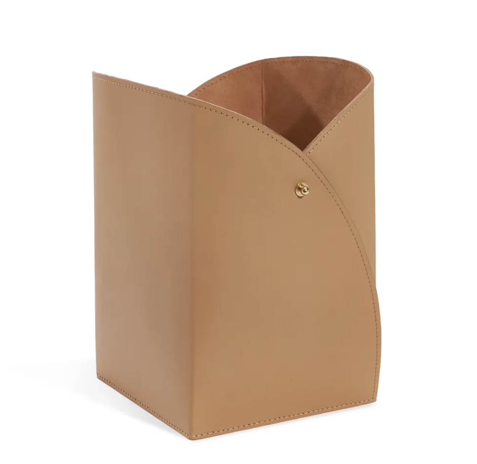 Tan leather magazine holder with curved silhouette and gold hardware for curated home decor.