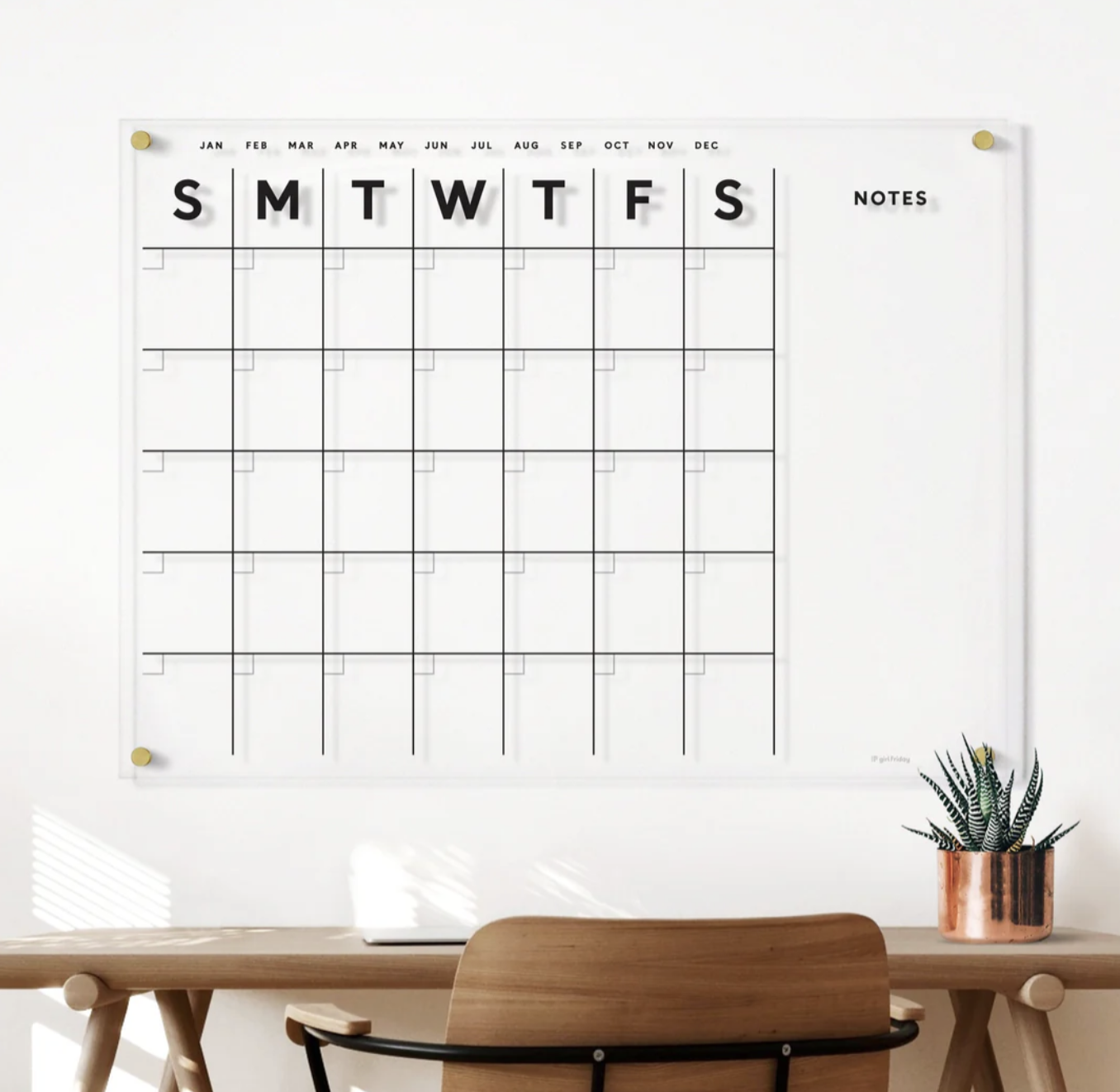 Minimalist wall calendar and desk organization with potted plant and wood furniture.