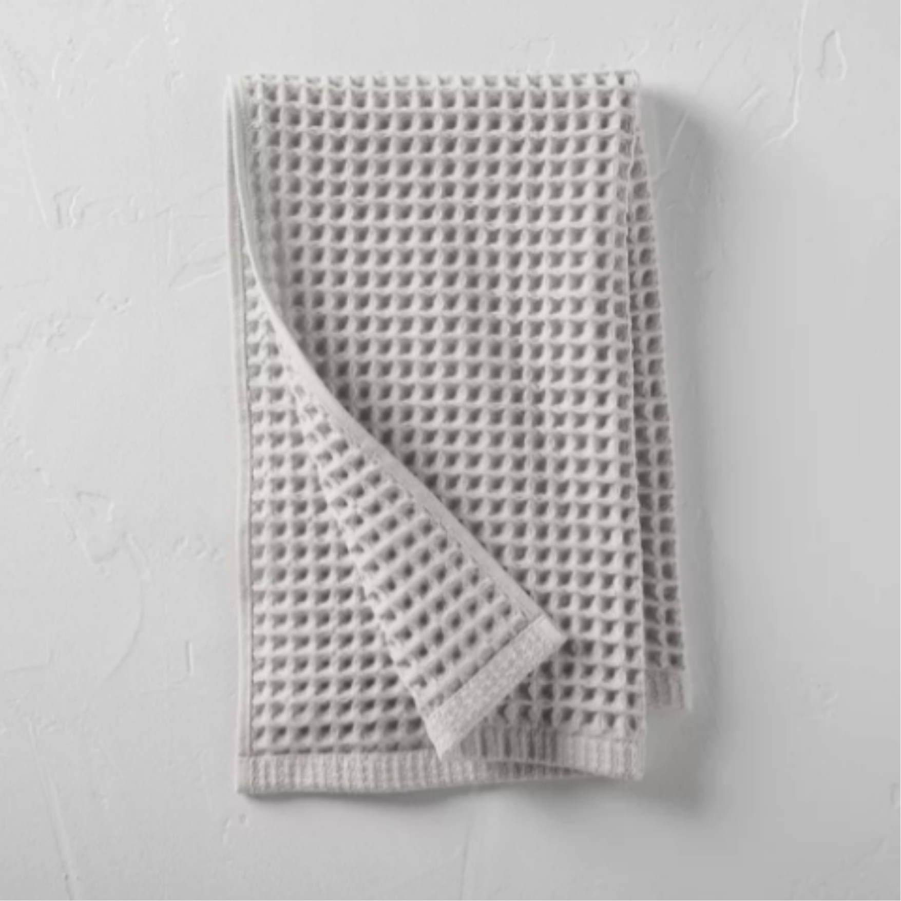 Close-up of a white mesh adhesive bandage on a white textured surface.