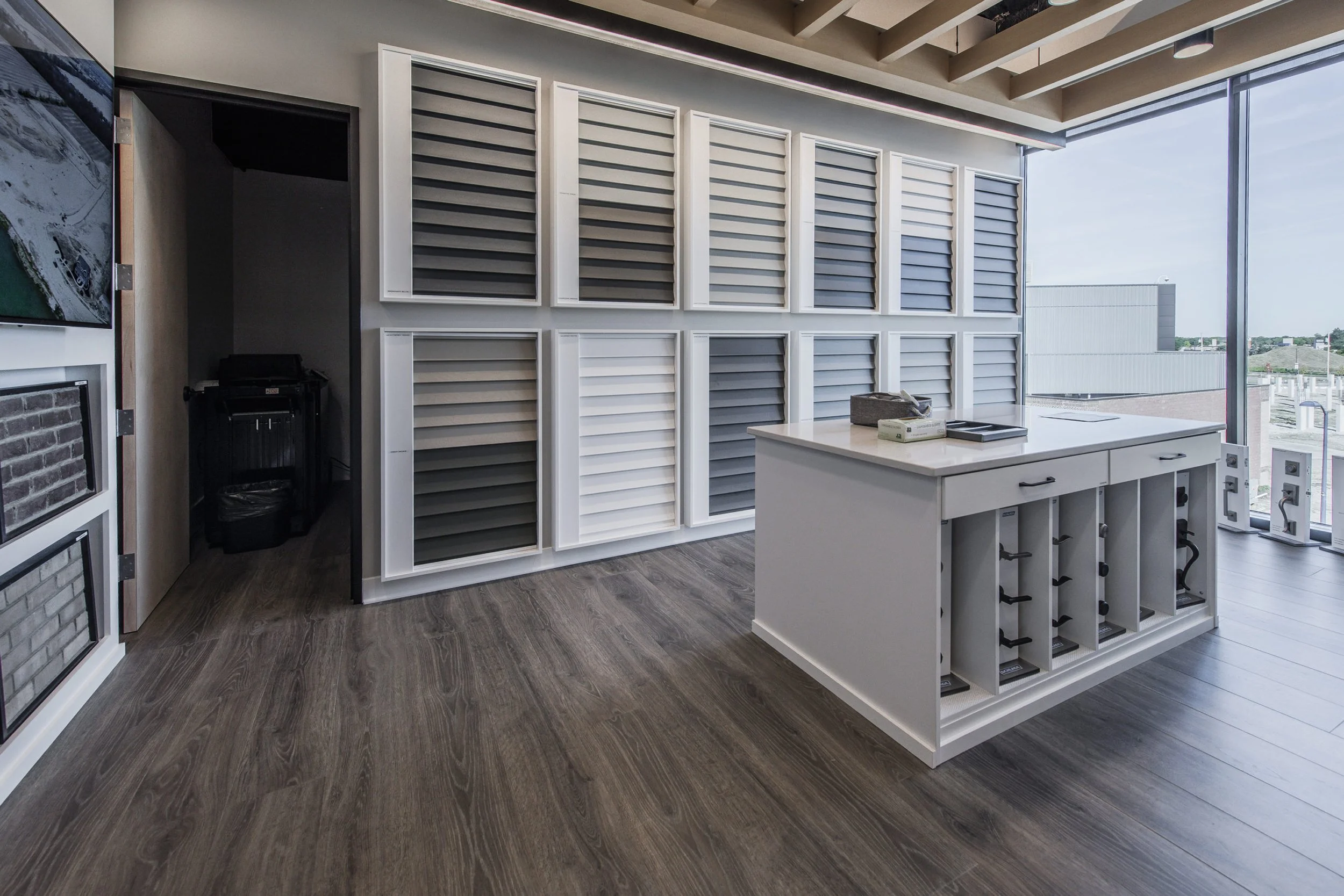 A design showroom featuring wall-mounted exterior siding samples and a central storage island with shelving.